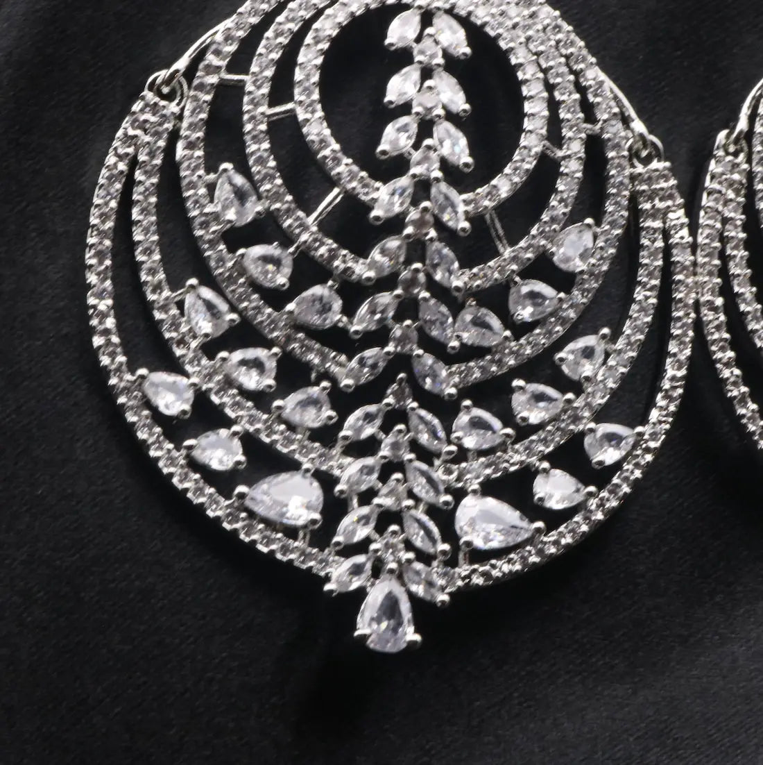 bottom part of American diamonds earrings with clear gemstones on a black background