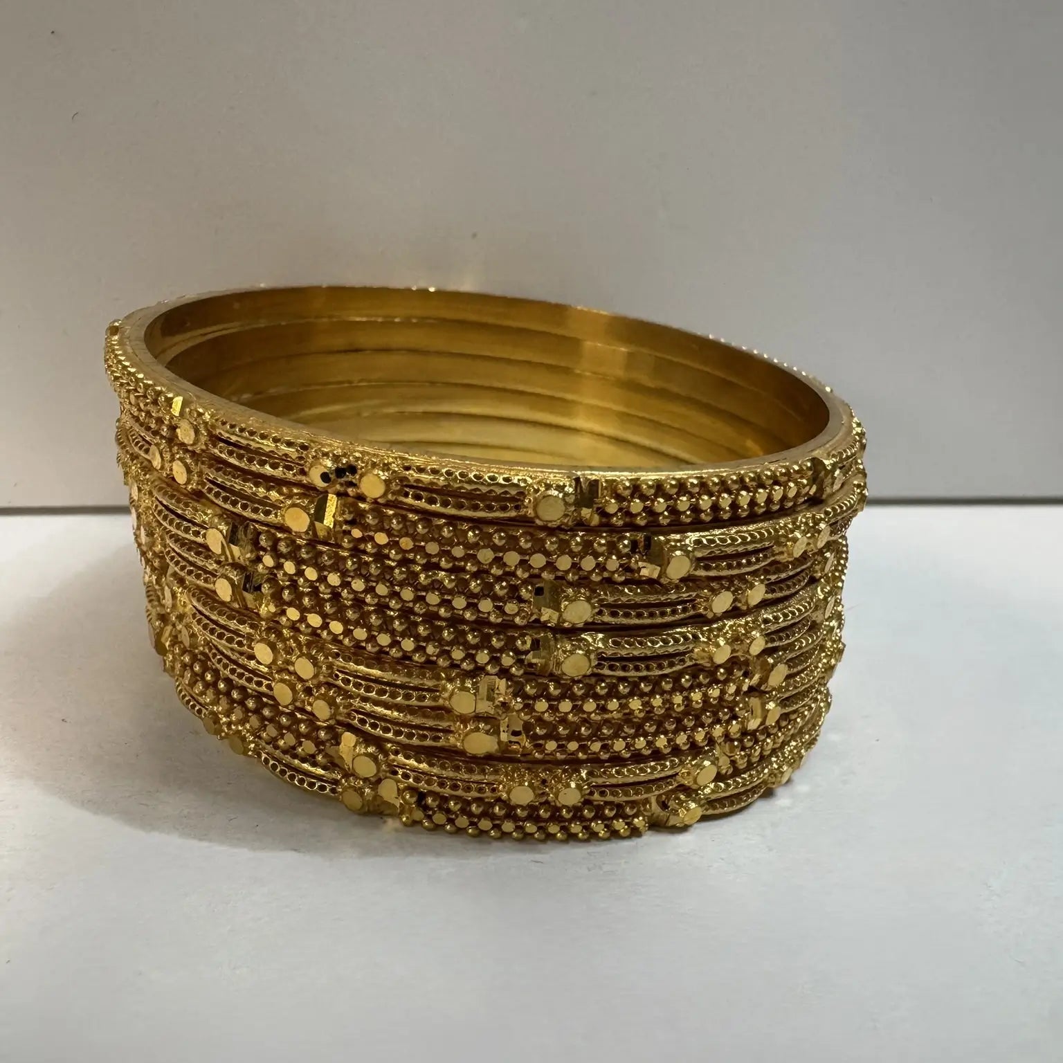 set of 8, 22k gold plated bangles on a white background