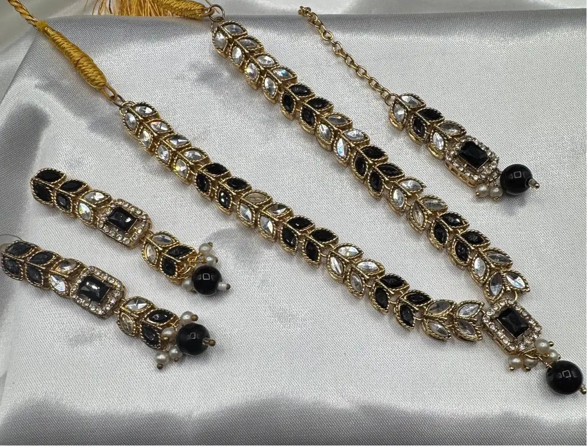 Set of gold and black jewelry on a white satin surface