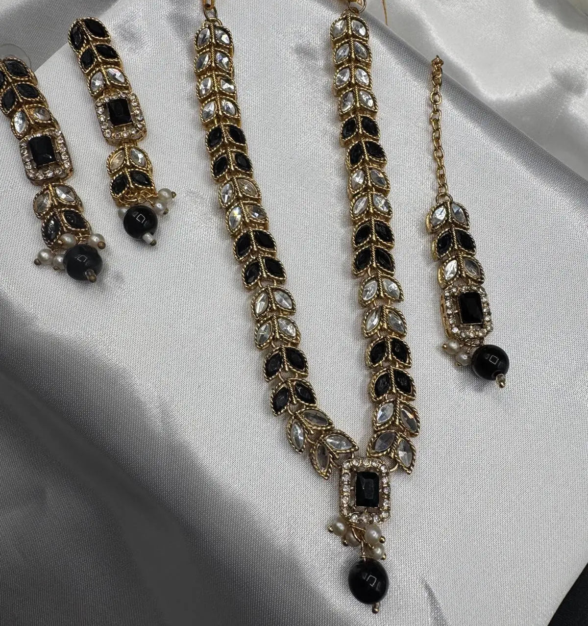 Jewelry set with necklace, earrings, and teeka on a white fabric background