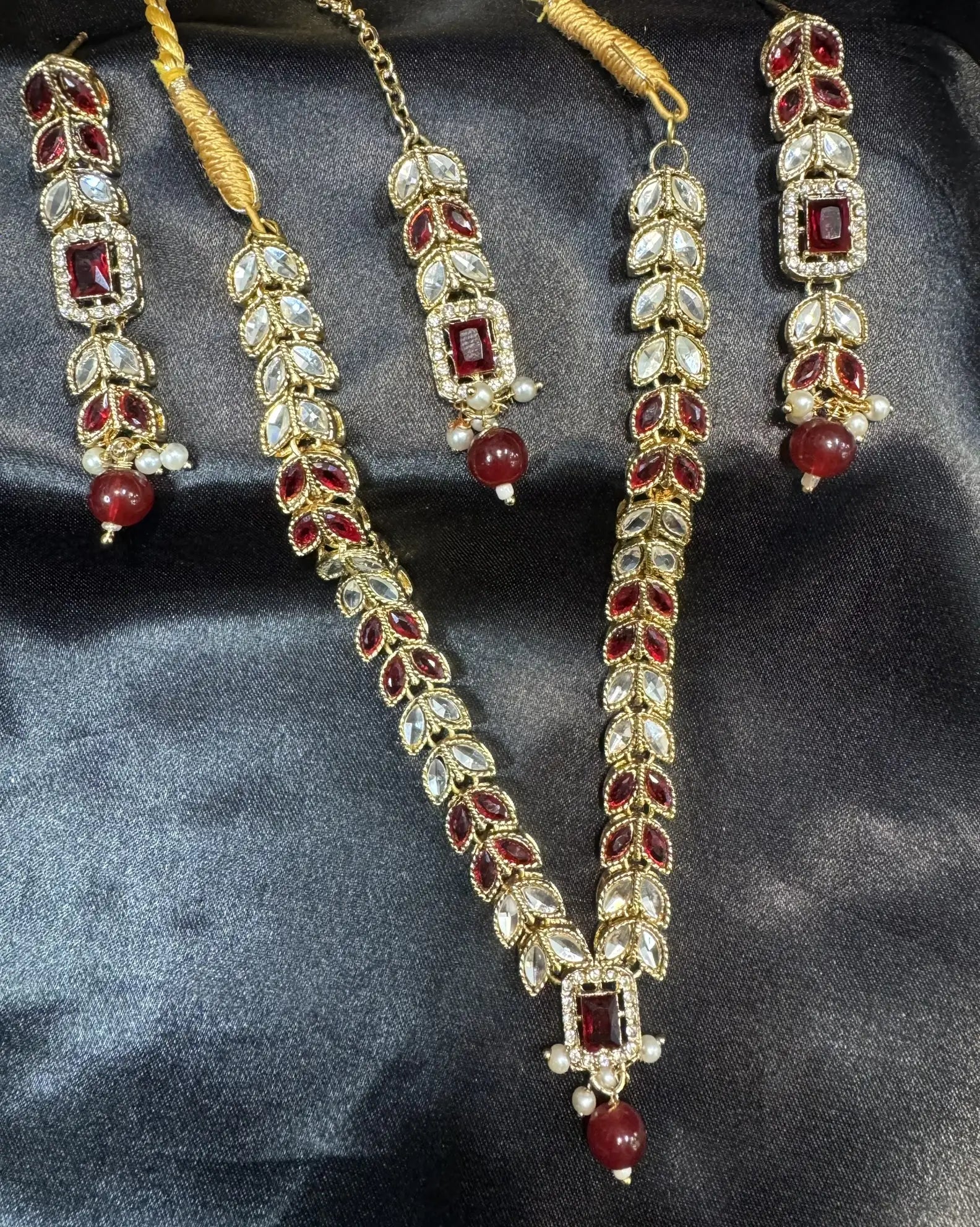 Bloom necklace set in ruby red with white kundan stones and beaded drops on gold base.