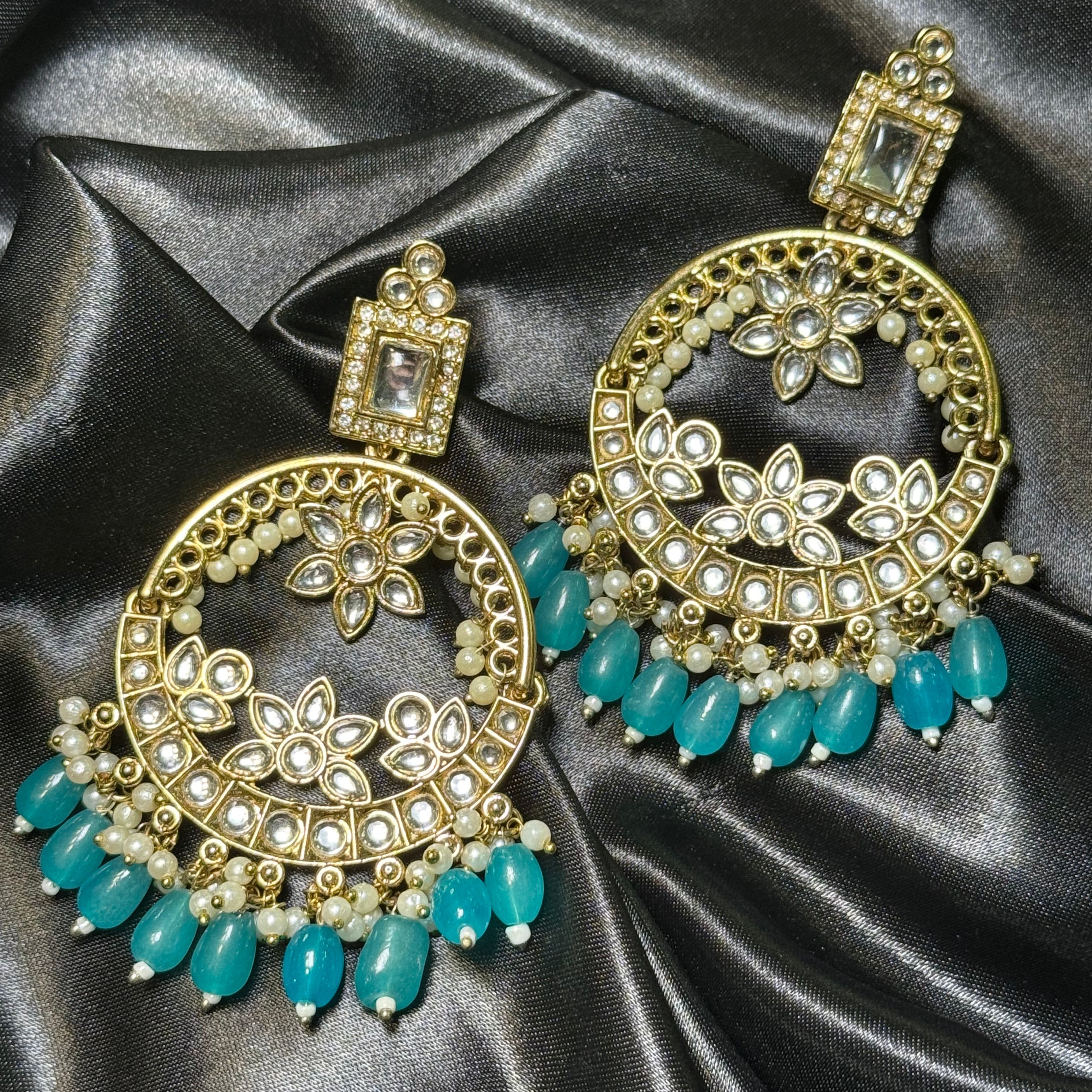 Ornate earrings with blue gemstones on a satin background