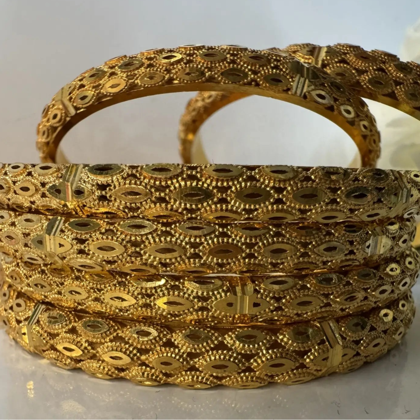 Set of gold bangles with intricate designs on a light background