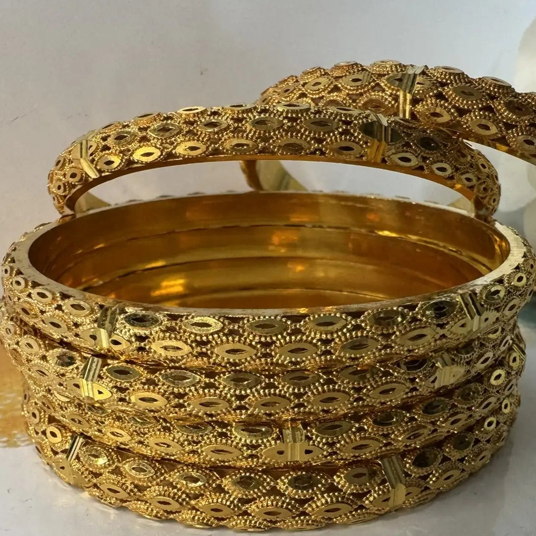 Set of gold bangles on a white surface