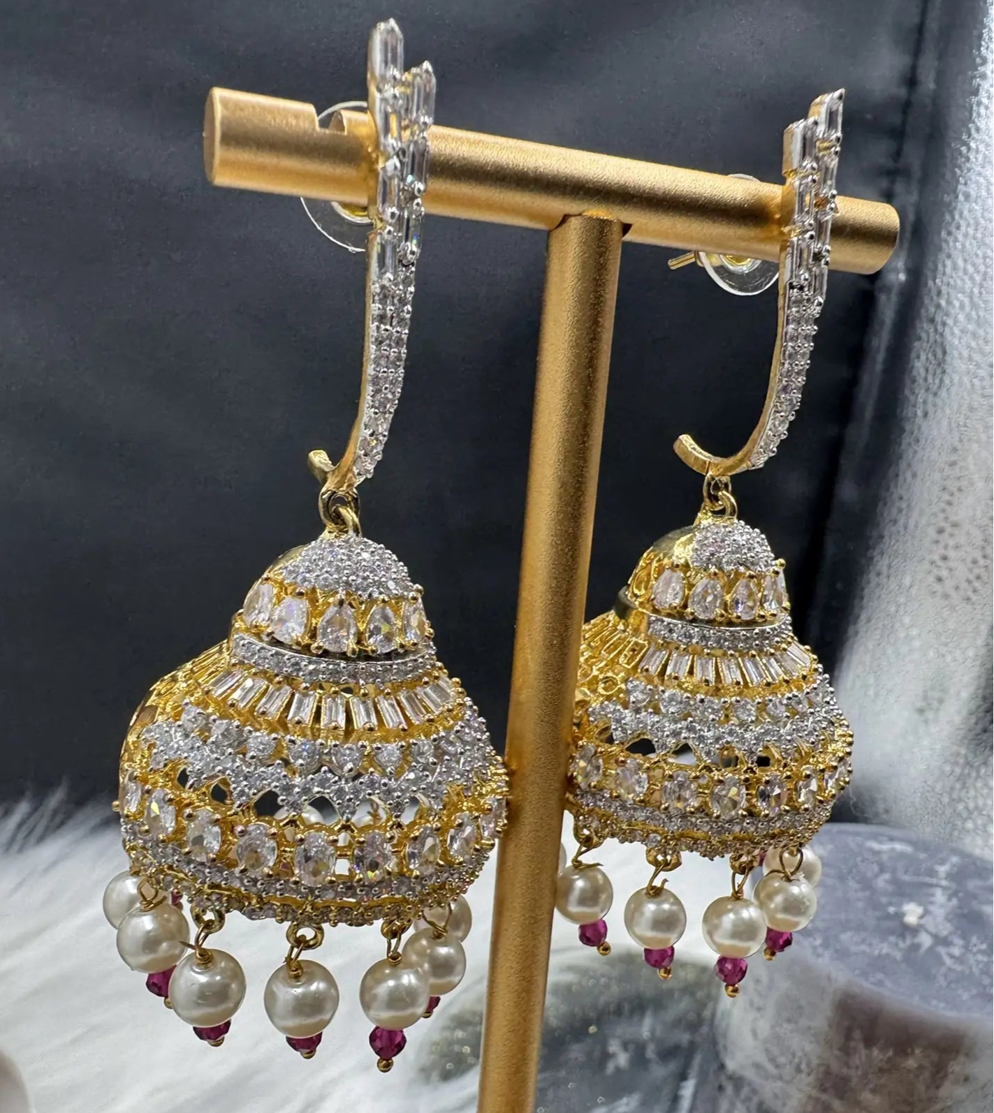 left side view of Pakistani design jhumkay with jarao craftsmanship. Clear gemstones with pearl accents providing an exquisite touch.