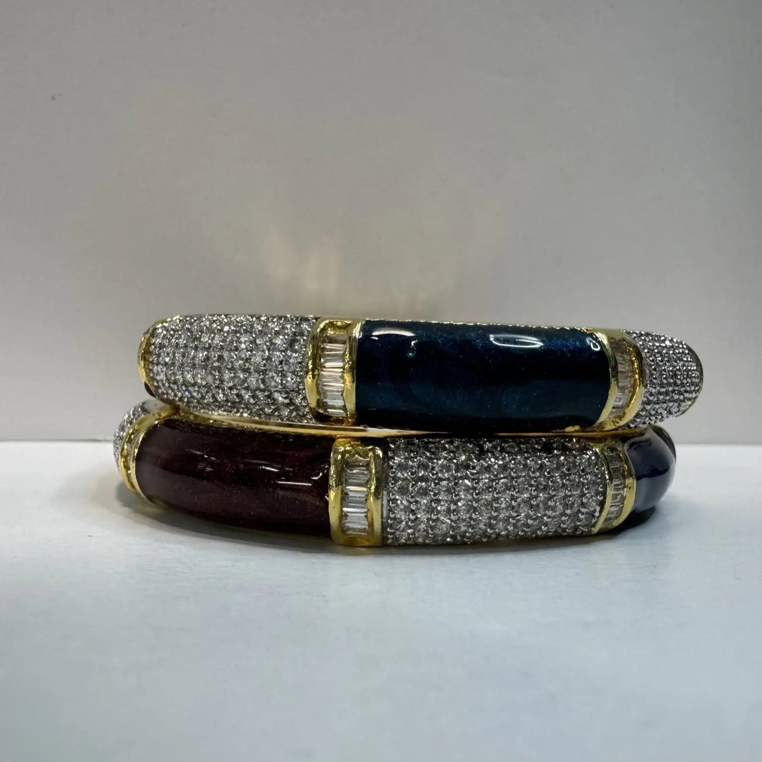 Two bangles with American diamonds and green and maroon solid blocks with gemstones on a light gray background