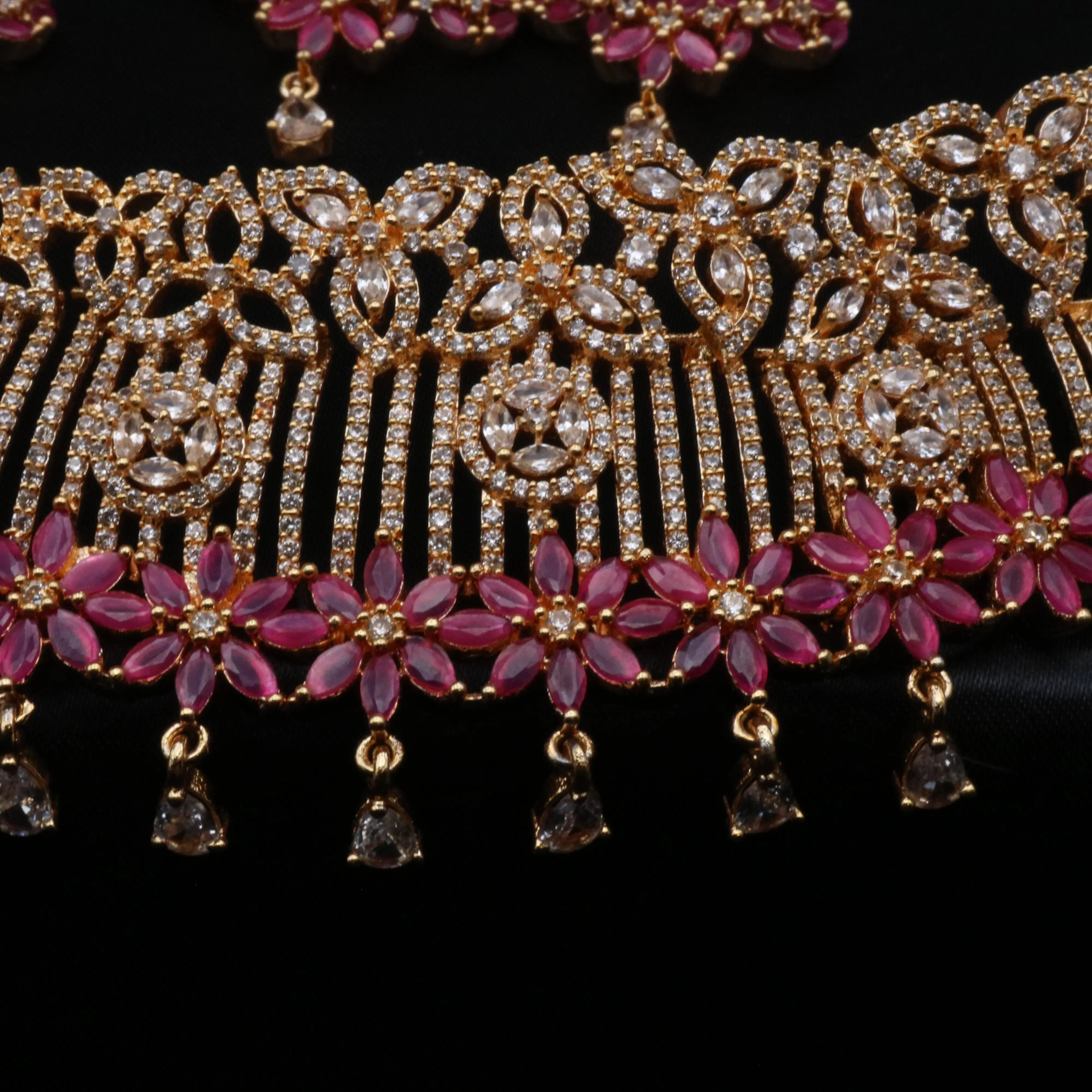 Macro view showing American diamond floral patterns and pink gemstone detailing on gold-plated necklace.