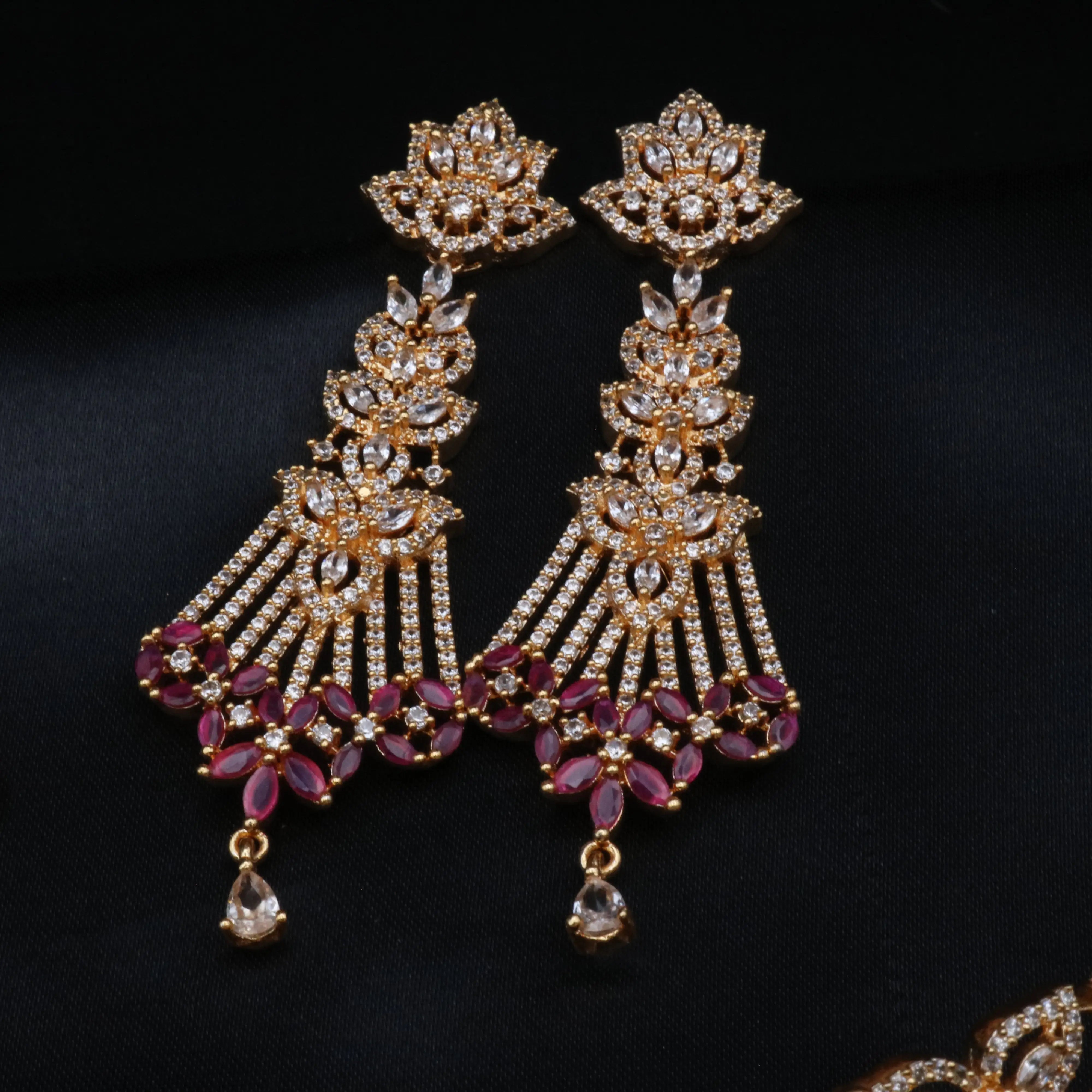Detailed view of long bridal earrings with cascading CZ and ruby accents in floral motifs.