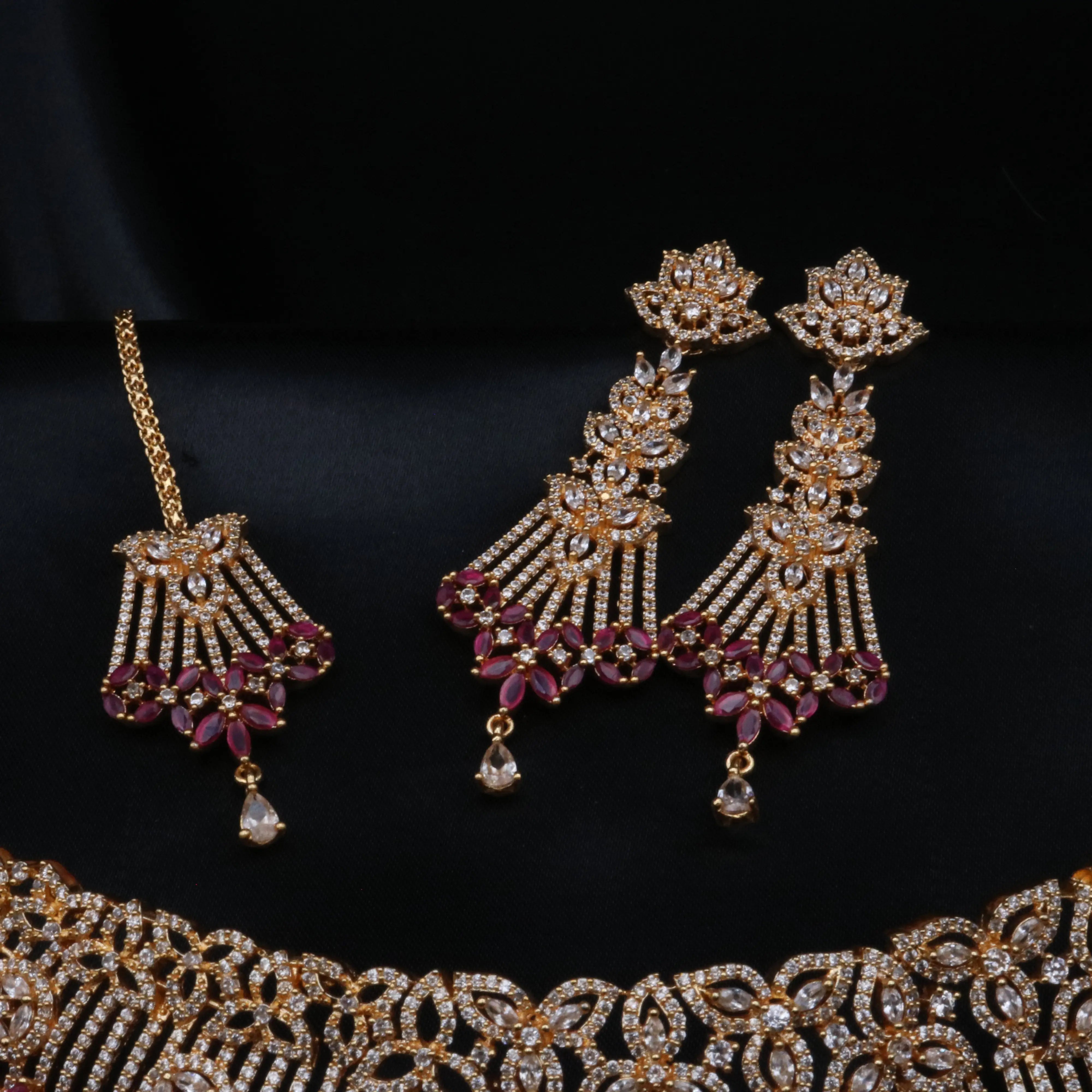 Close-up of earrings and maang tikka from Cherry Blossom set with floral patterns and ruby accents.
