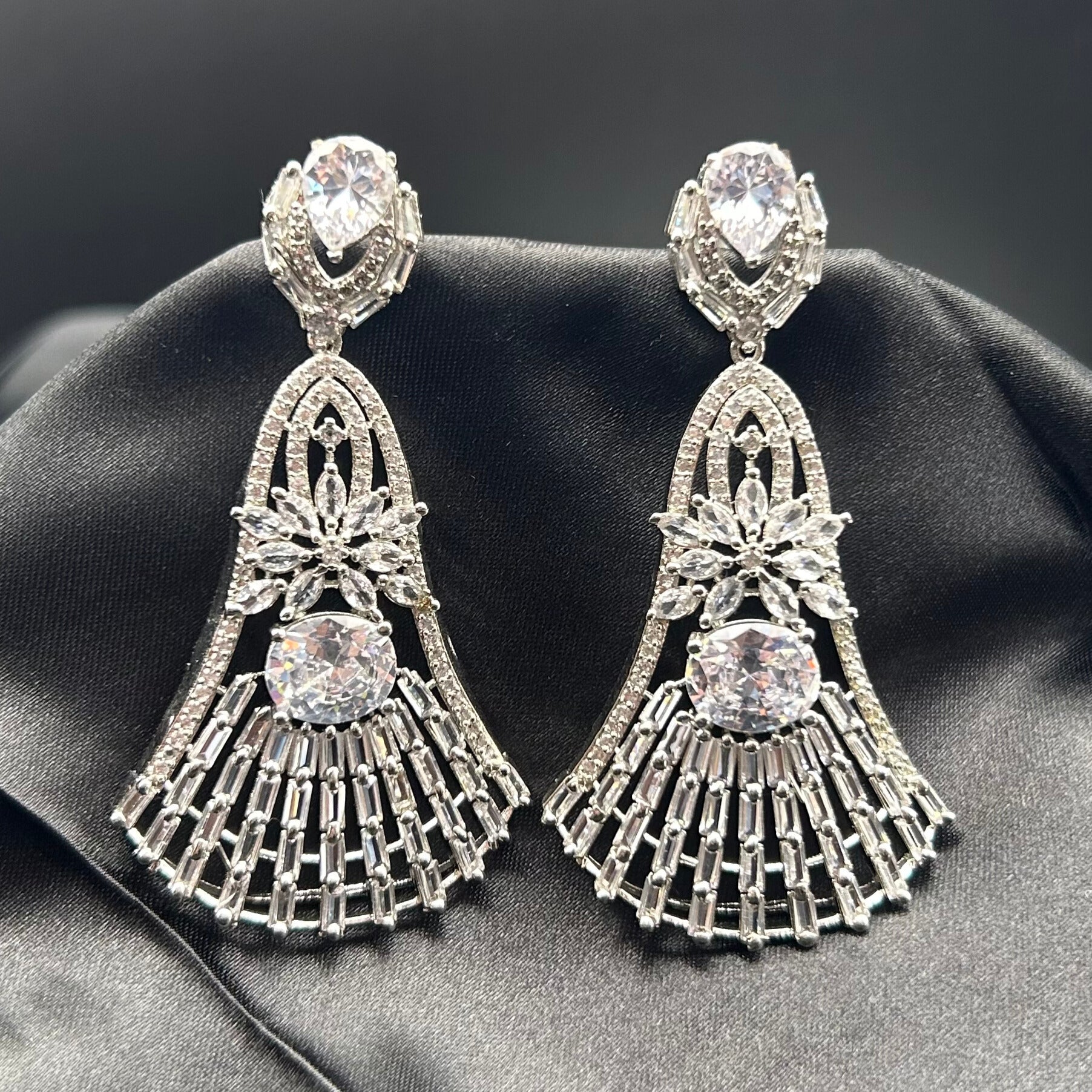 A pair of silver and American diamond earrings with intricate design and drop style.