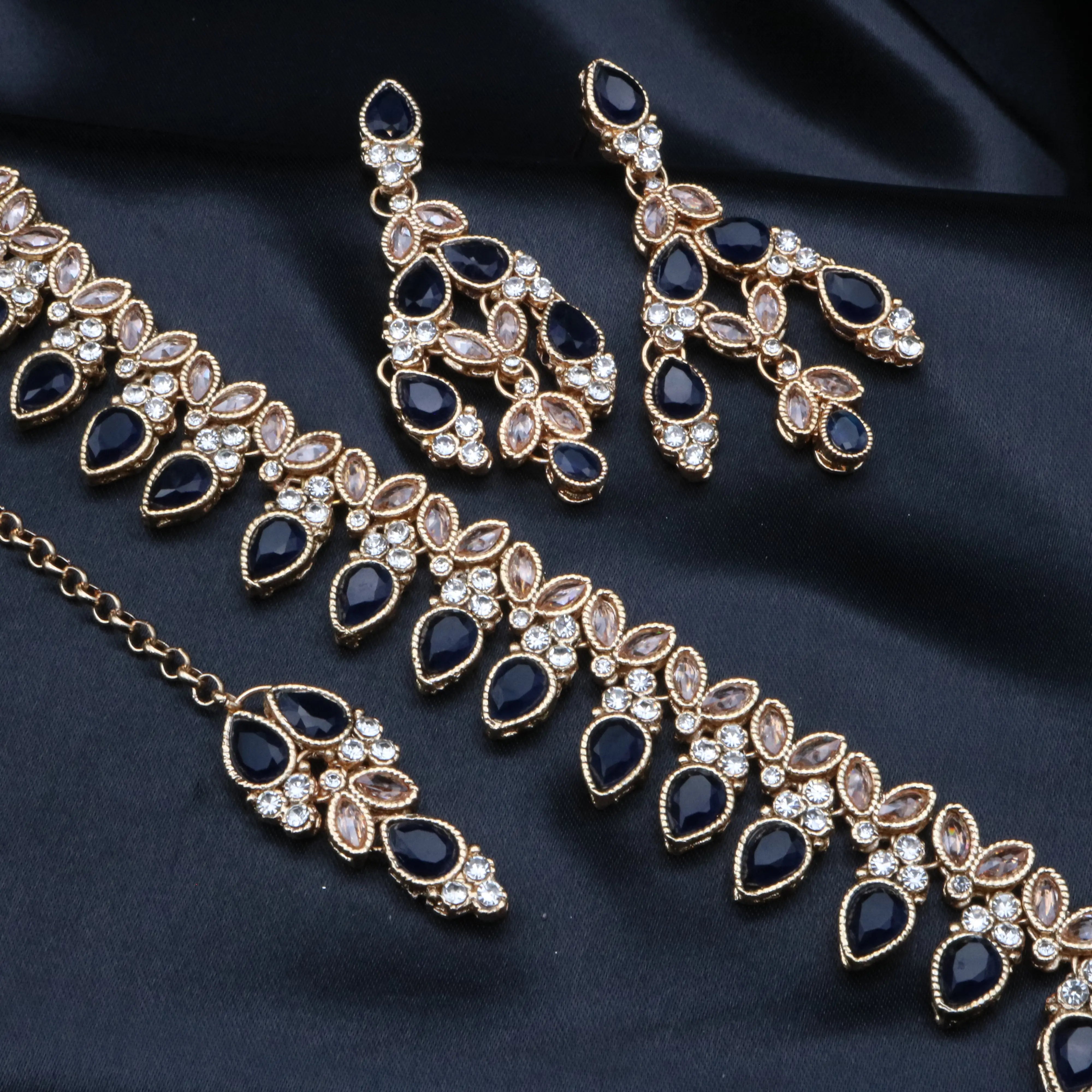 Detailed view of navy blue teardrop stones and champagne marquise CZs in matching necklace, earrings and teeka.