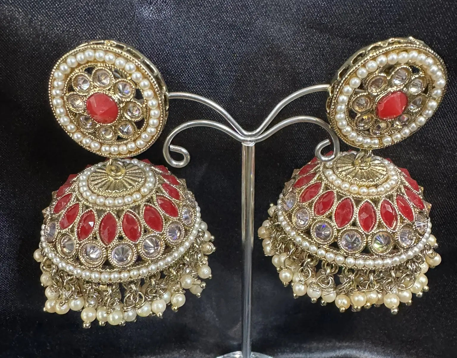 Jhumka earrings with red gemstones and gold accents on a black background