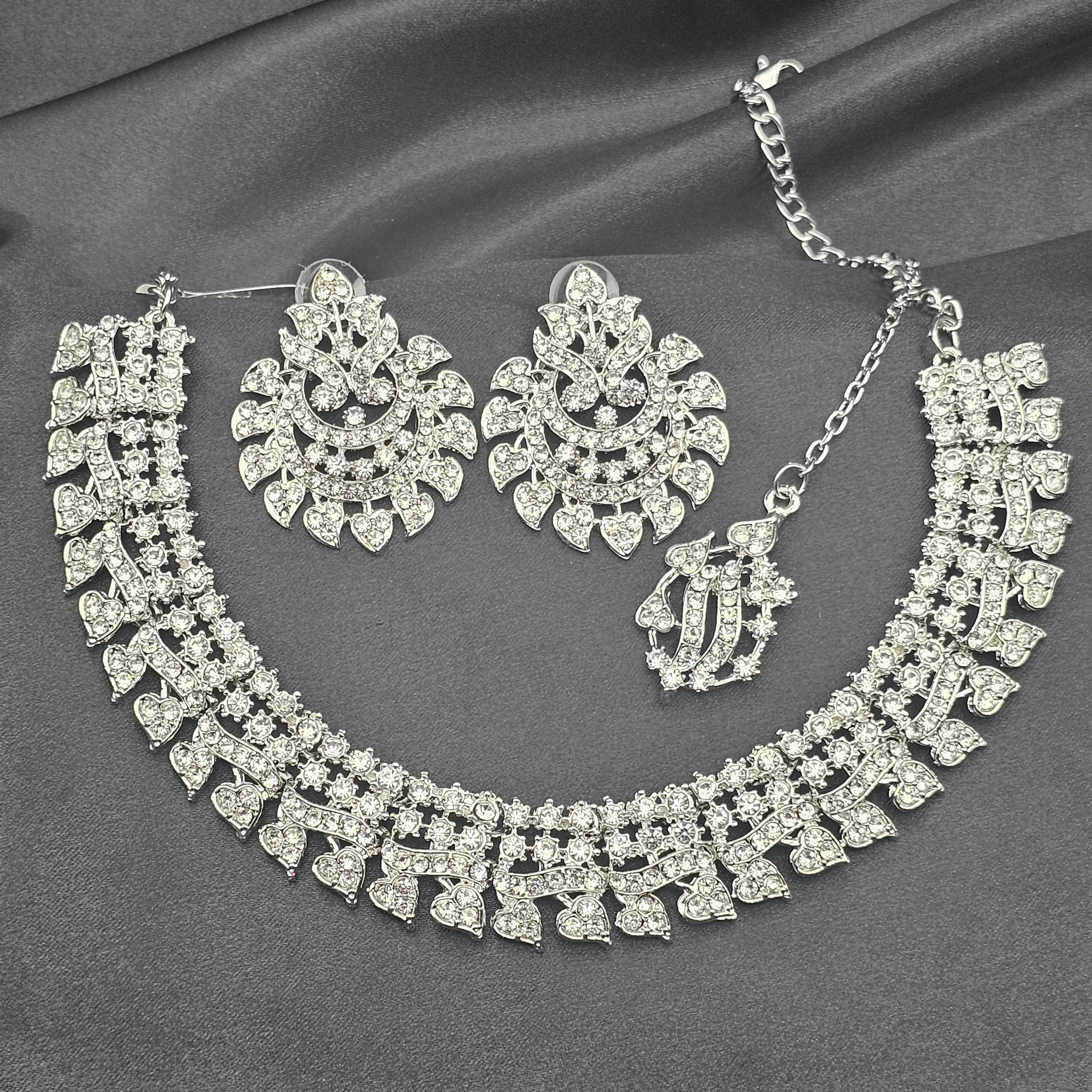 Cupid silver CZ necklace set with heart-shaped stones, earrings, and maang tikka on grey satin background