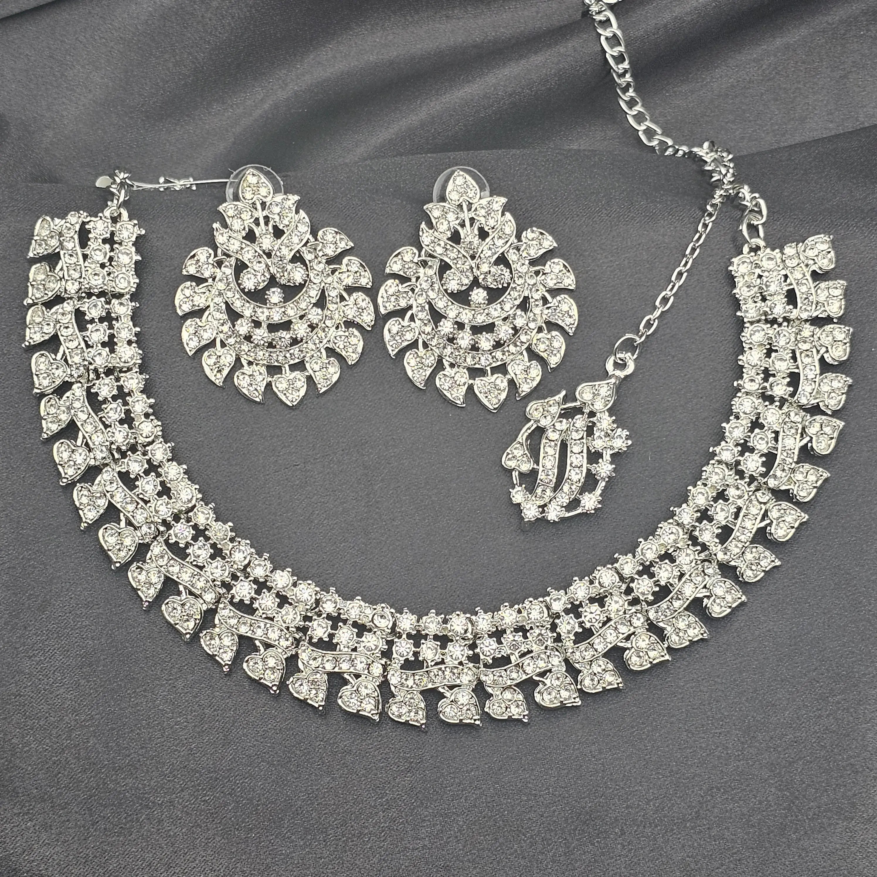 Close-up of Cupid bridal necklace set featuring zircon hearts and chandelier earrings laid flat