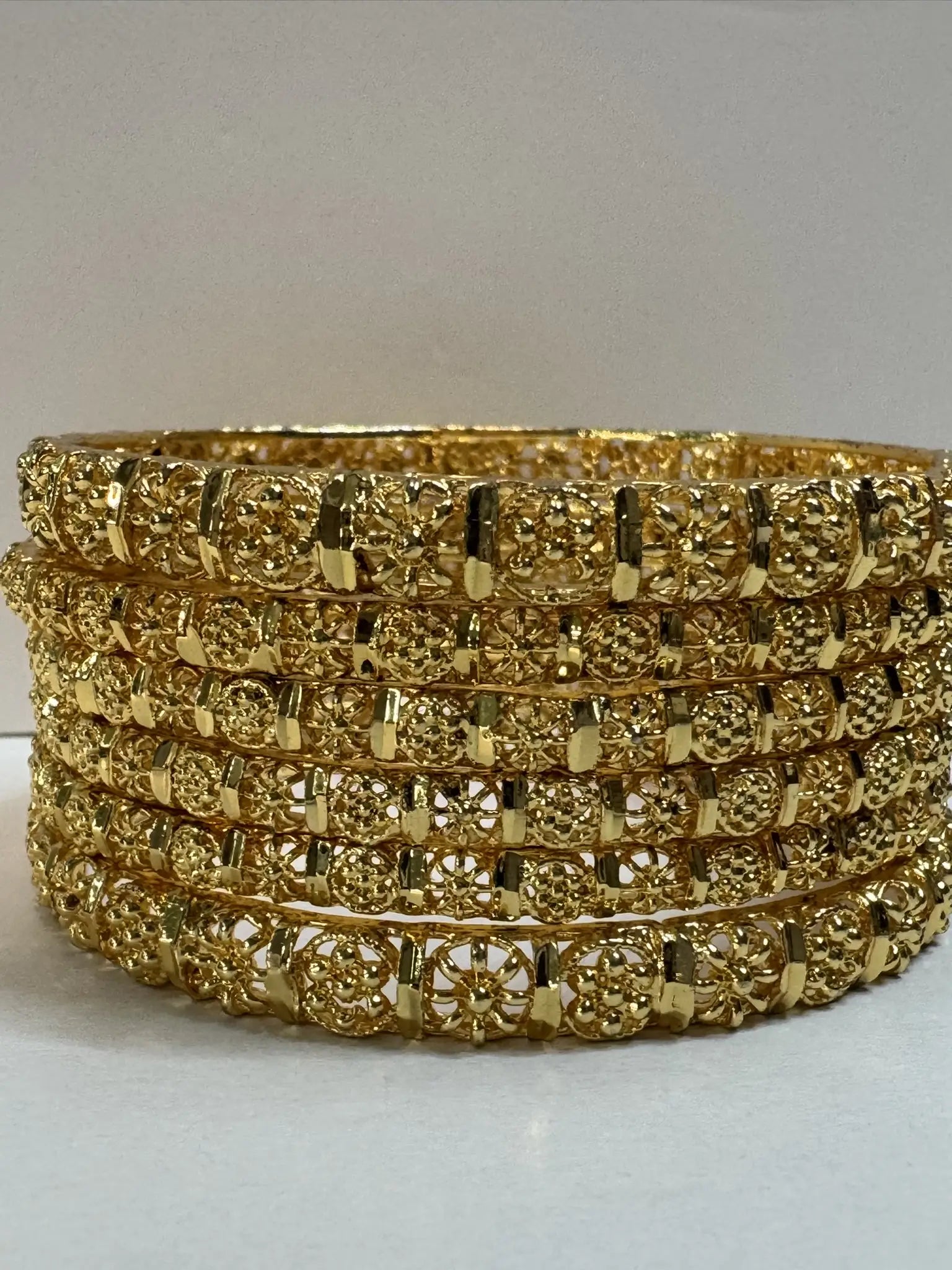 set of 6 gold plated bangles on a light gray background