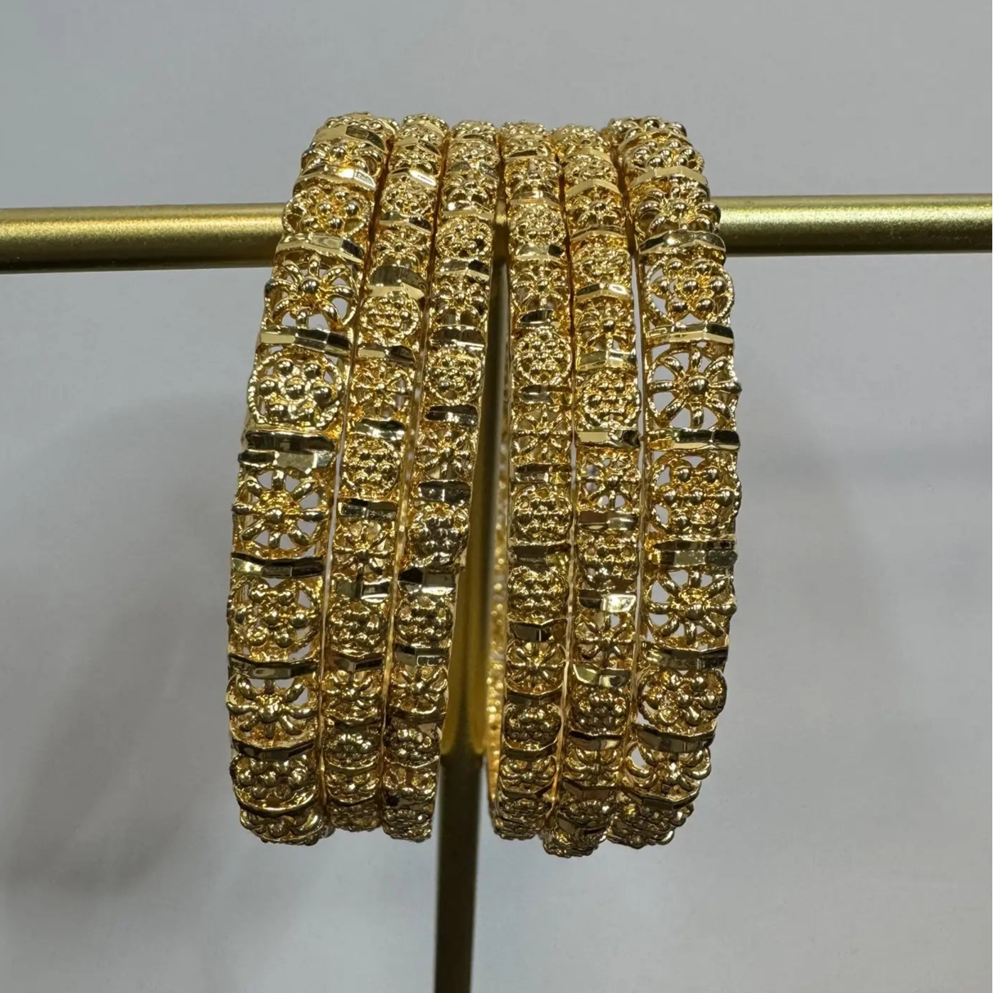 set of 6, gold plated and stainless steel bangles on a stand against a plain background