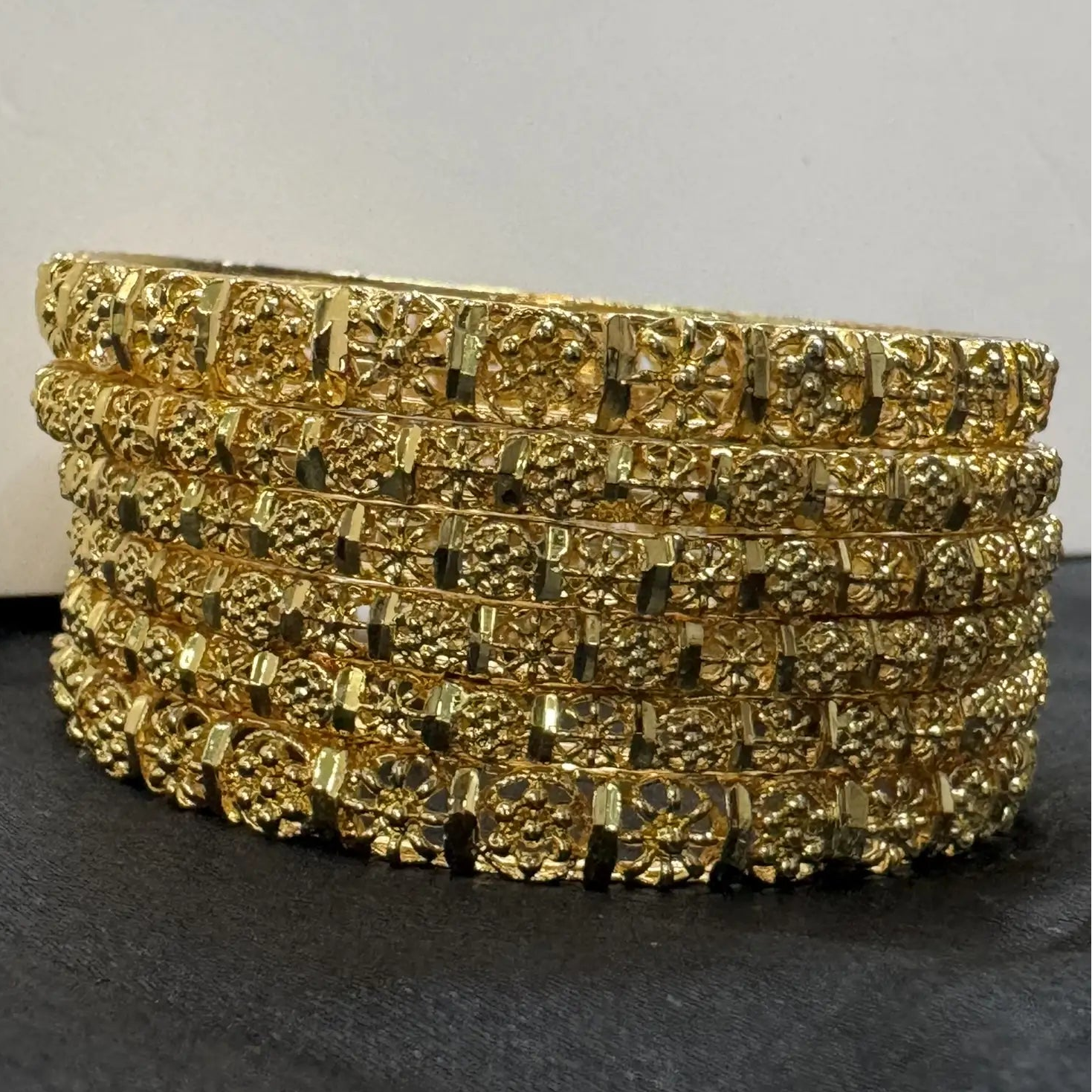 set of 6, gold plated and stainless steel bangles on a light gray background and silk cloth