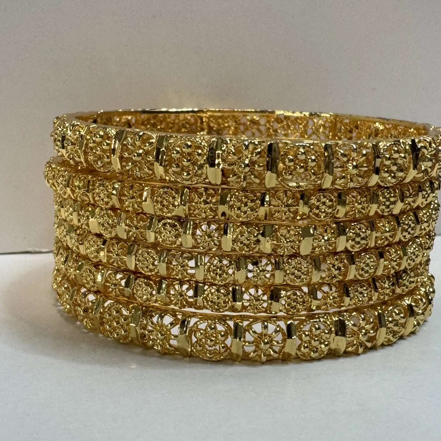set of 6, gold plated and stainless steel bangles on a light gray background