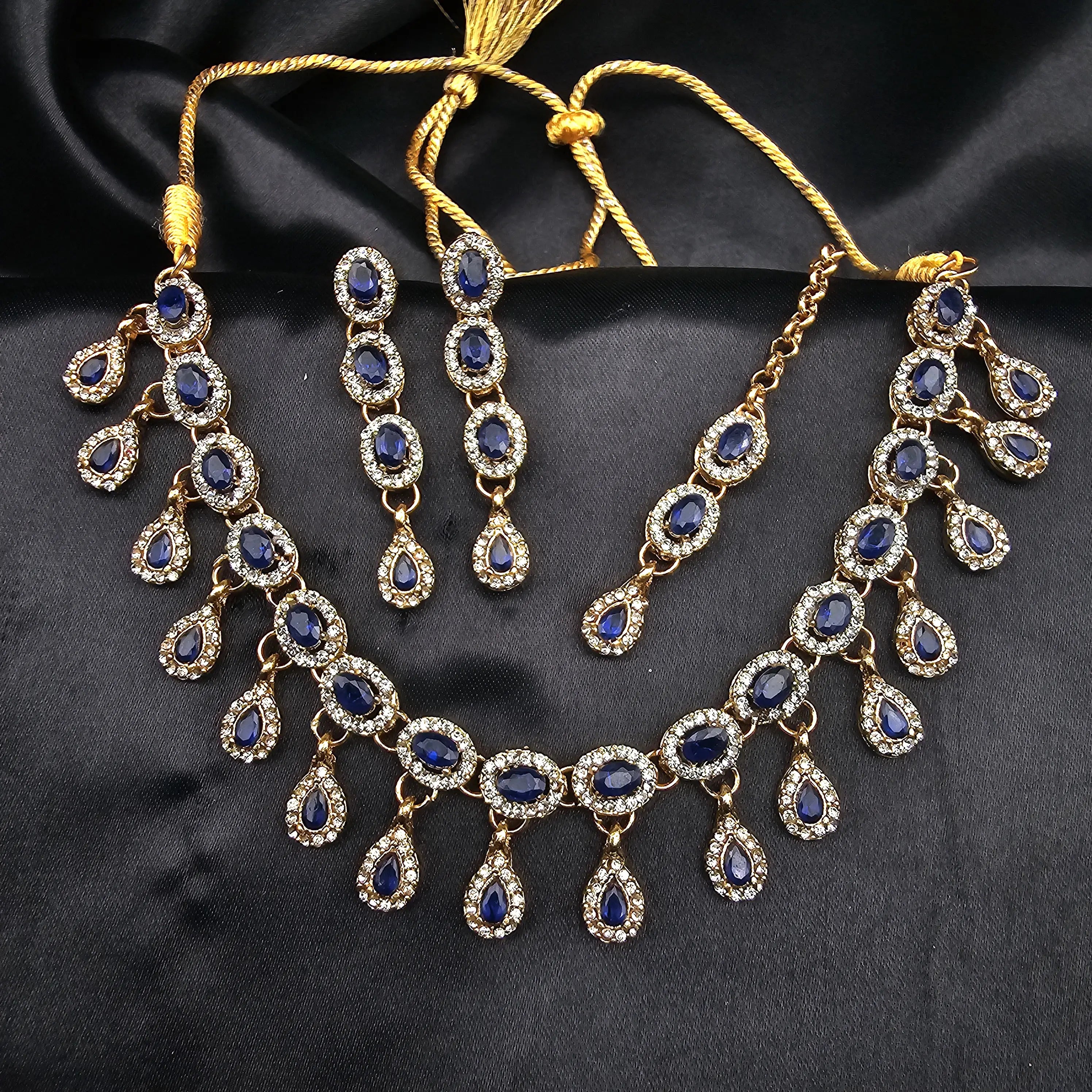 Sapphire blue Daint necklace and earring set displayed against black satin with deep blue CZ stones