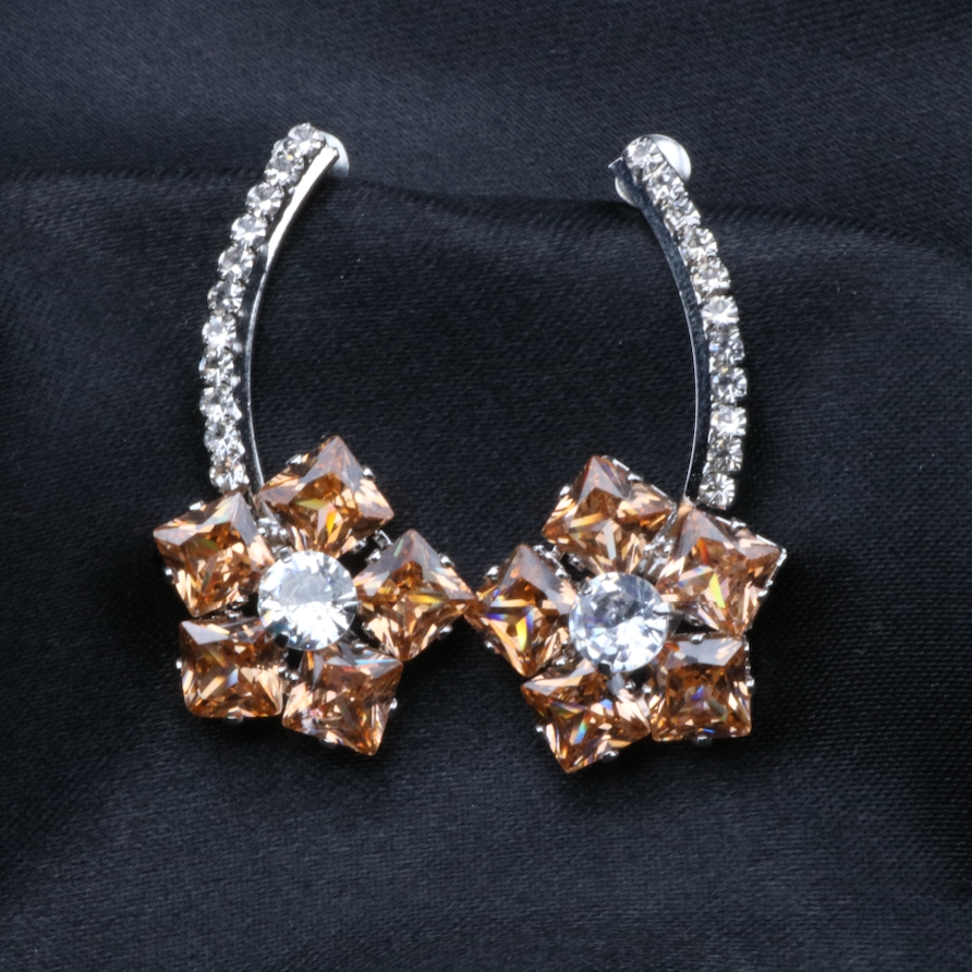 A pair of stainless steel and gold-plated earrings with champagne and clear American diamonds.