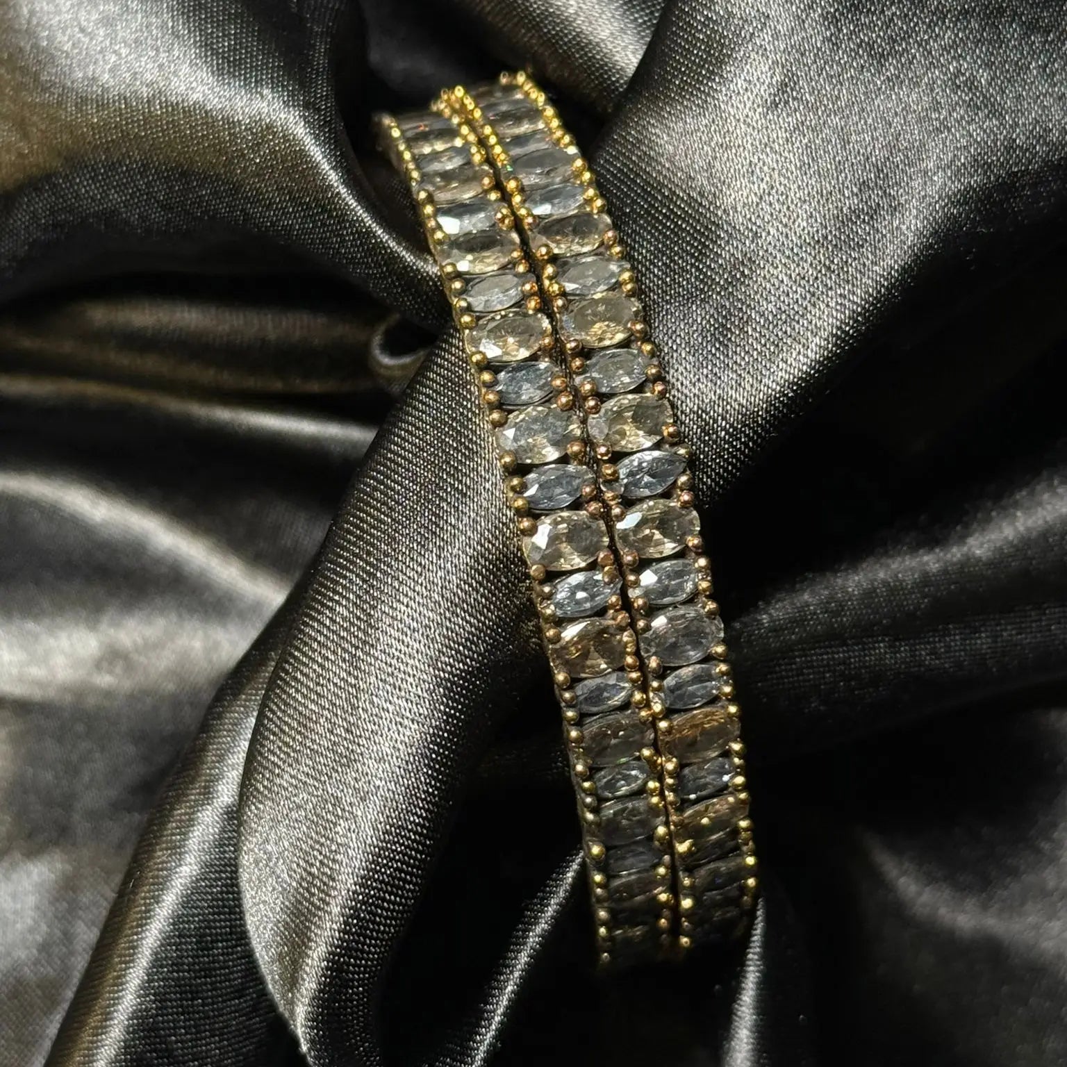 Slim gold beaded bangles with smoke grey stones on black satin