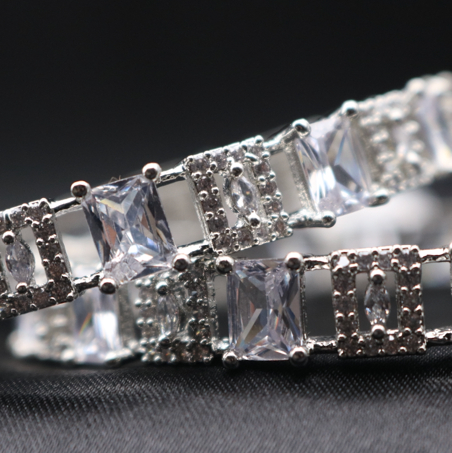 a closer look at silver bangle bracelet adorned with clear gemstones, showcasing its sparkle and design.