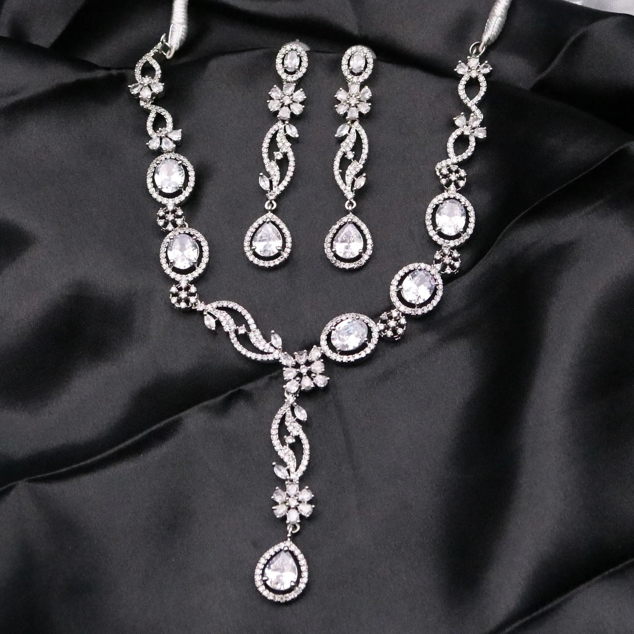 Full view of Diana necklace set with teardrop CZ earrings and floral detailing on black satin background