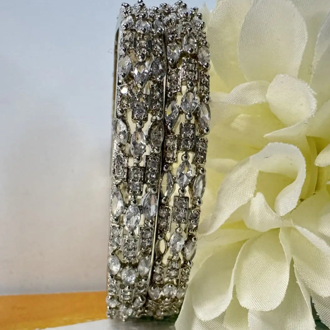 American diamonds bangles in silver with clear gemstones on white background and white flower at the back
