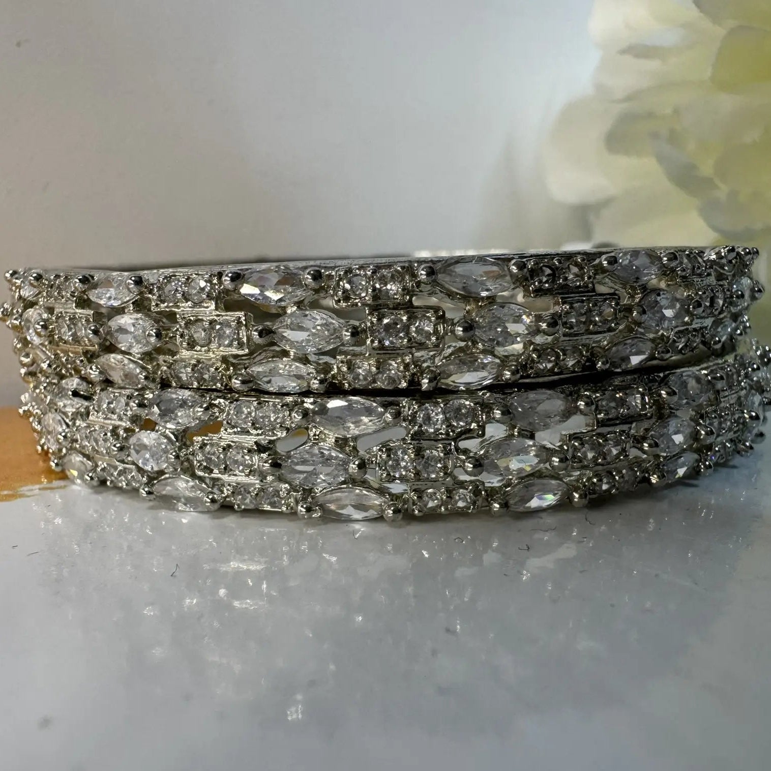 Stack of silver bangles with clear stones on a light background