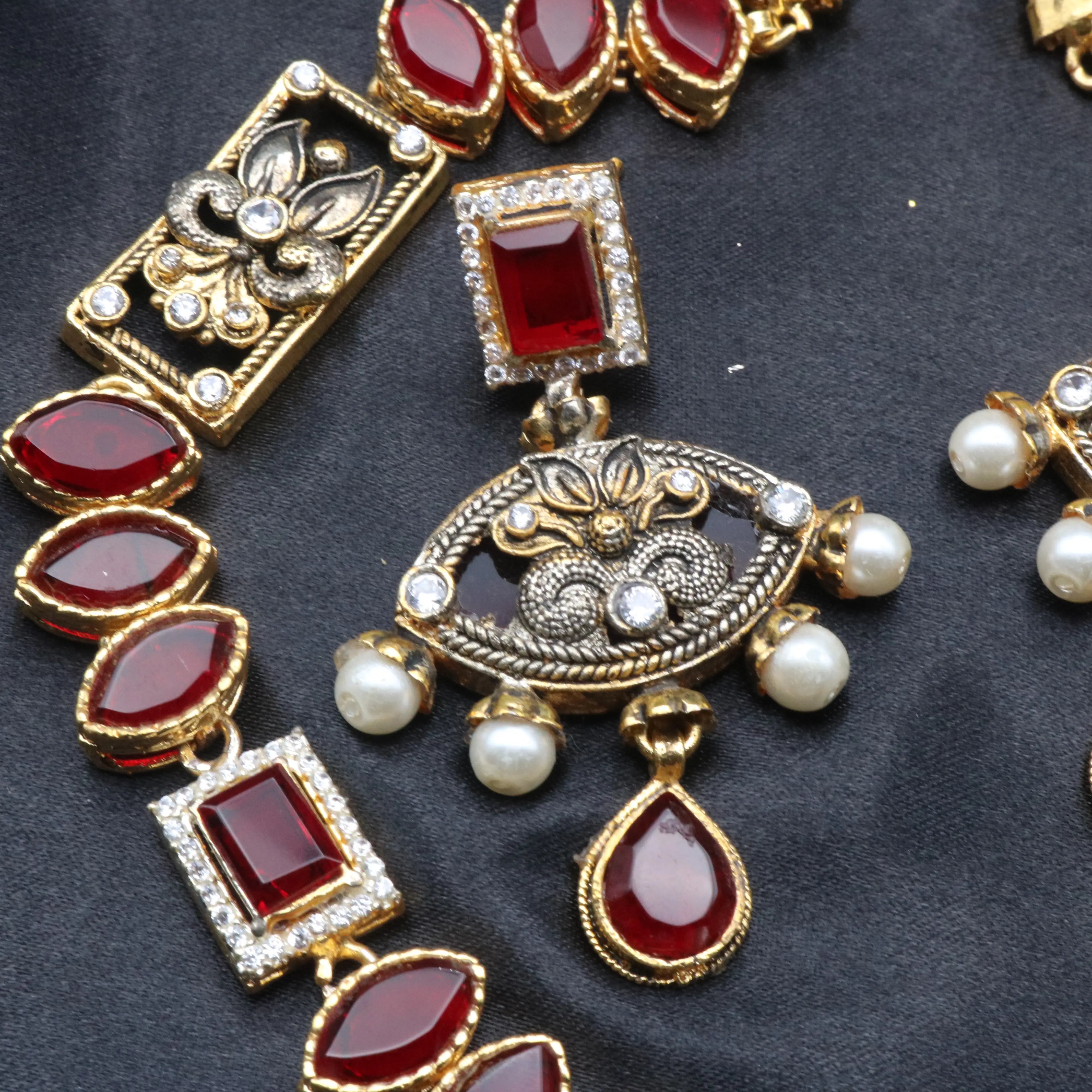 Close-up of Egypt necklace set showing antique gold pendant, ruby gemstone, and pearl drops.