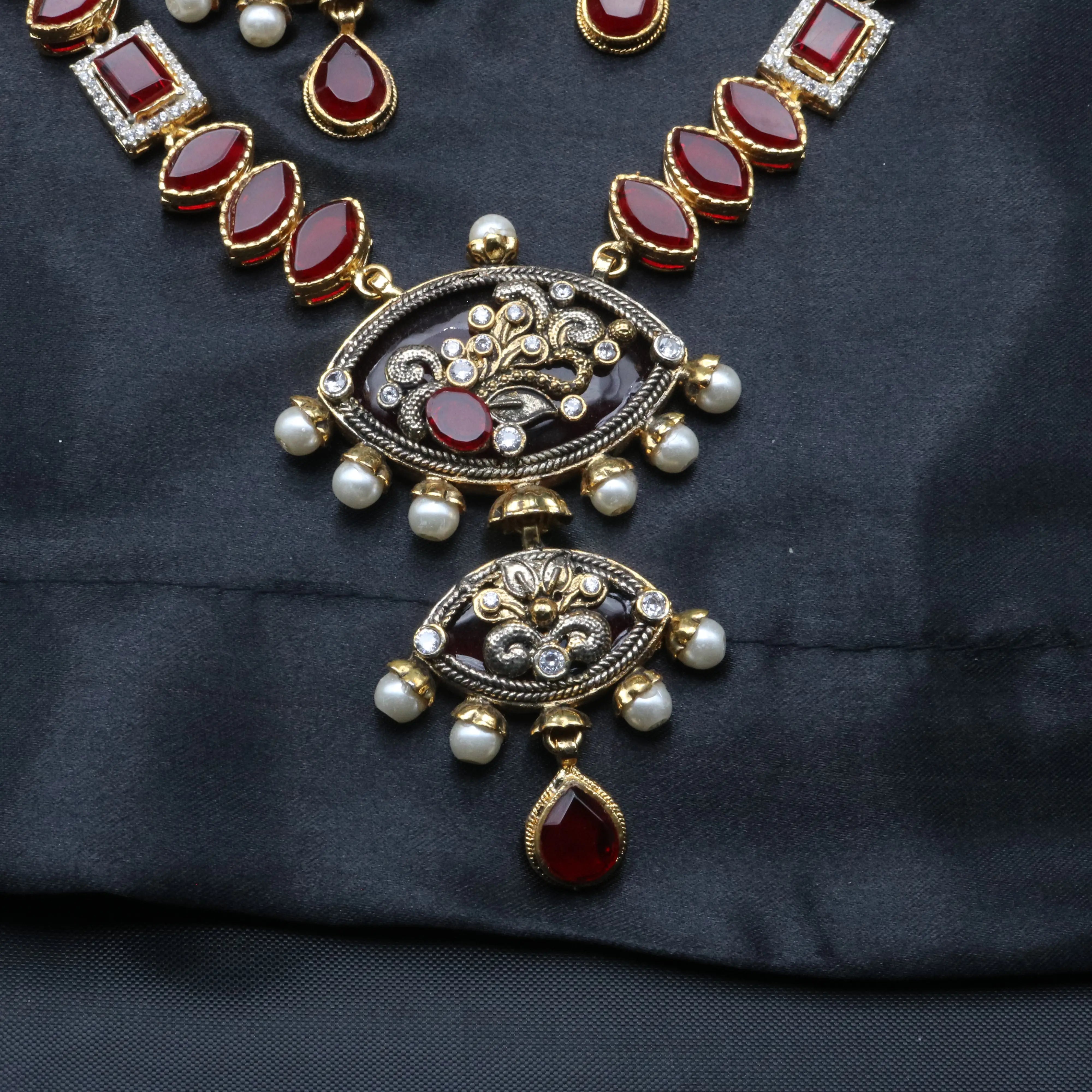 Close-up of the central pendant of Egypt necklace featuring floral engravings, ruby stone, and pearls.