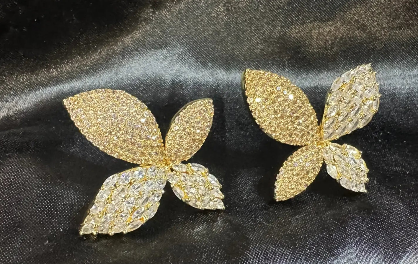 Gold butterfly-shaped earrings on a black fabric background