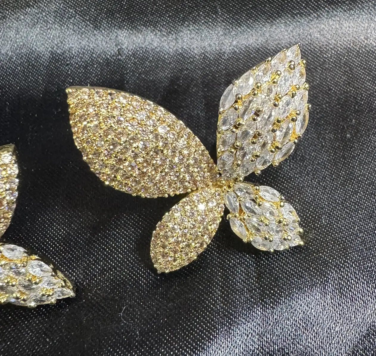 Gold and silver butterfly-shaped earrings on black fabric