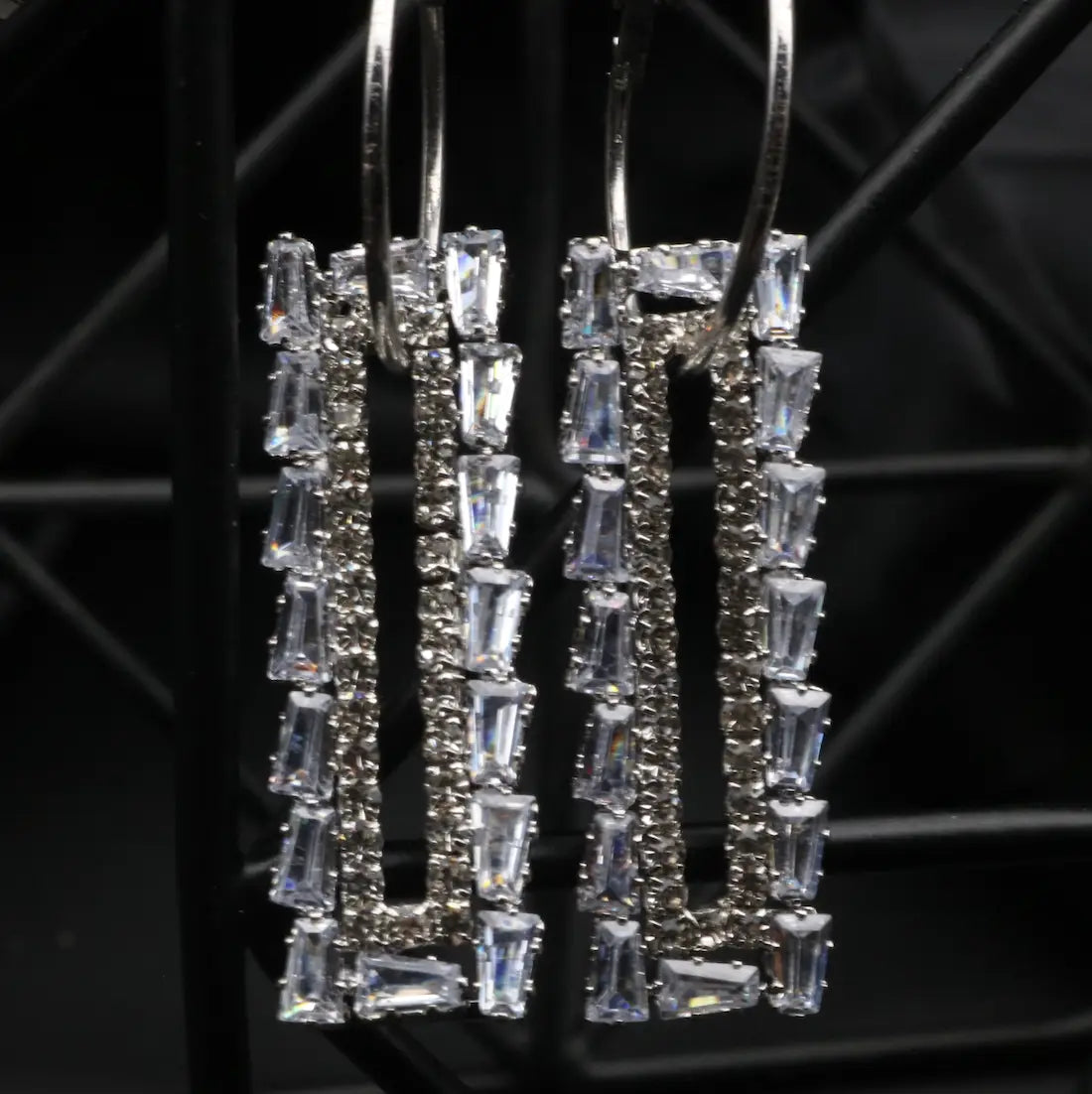 Silver earrings with clear gemstones on a dark background