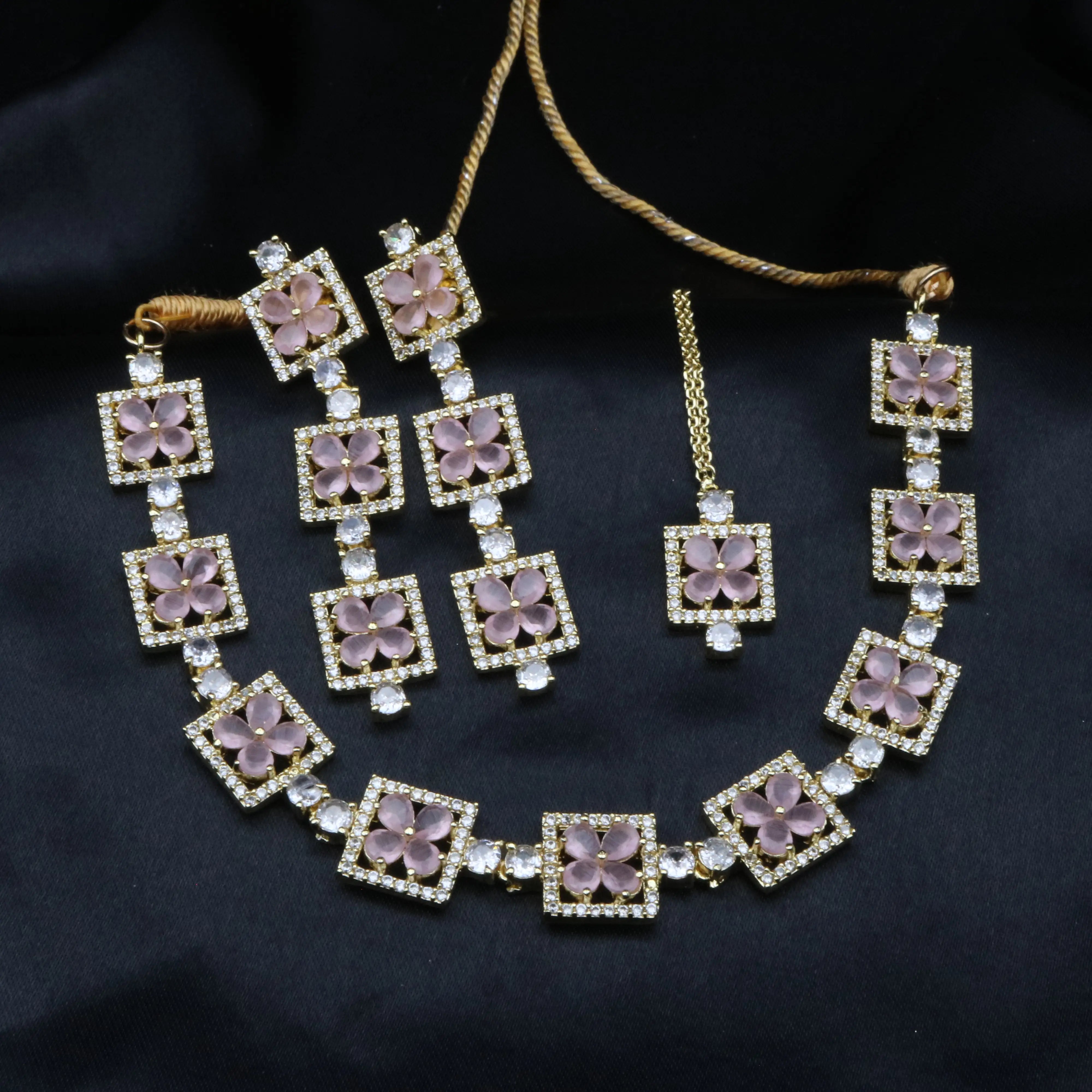 Full view of Fleur pink variant jewelry set with necklace and matching earrings on black backdrop.