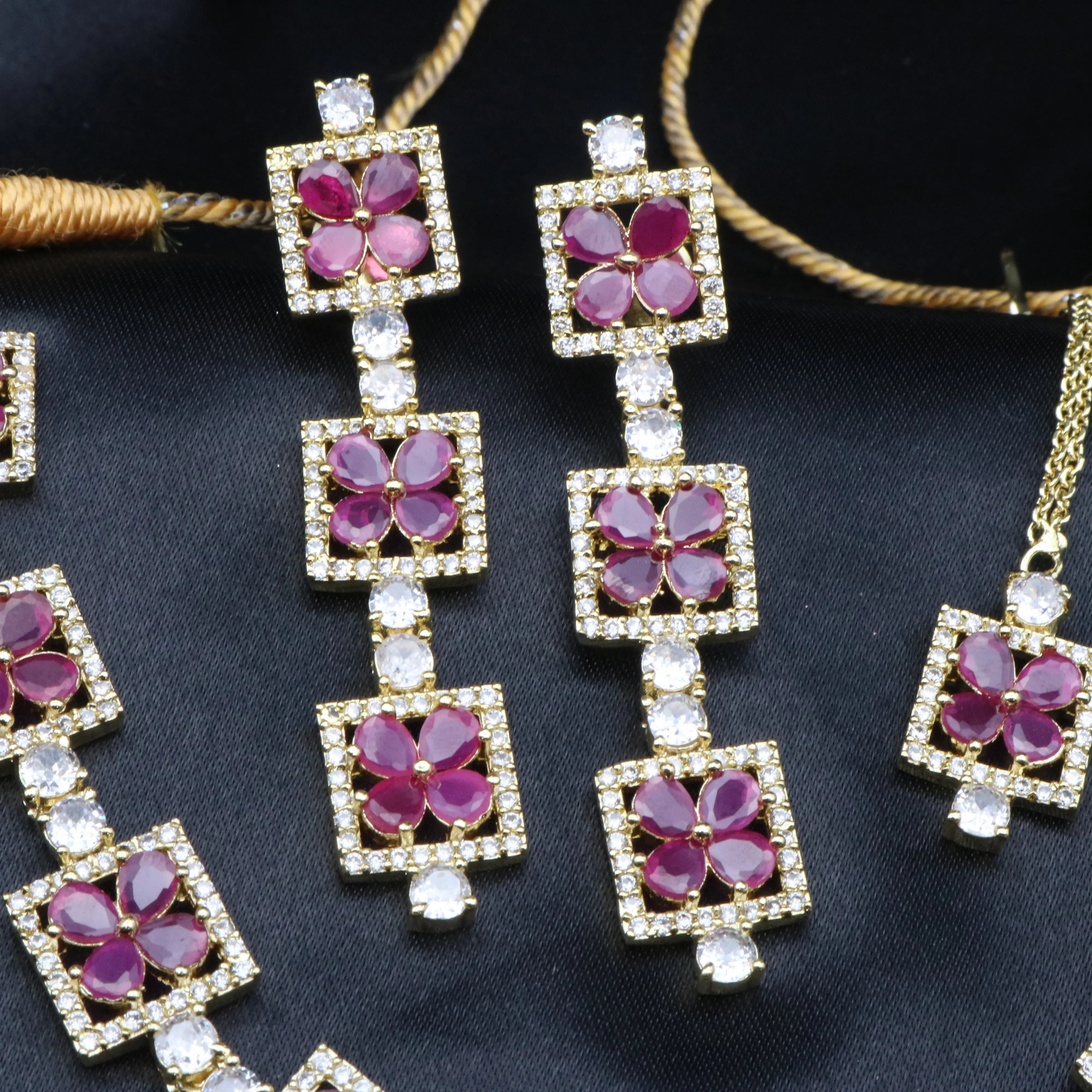 Detailed view of Fleur ruby red CZ earrings showcasing petal cut stones and pavé borders.
