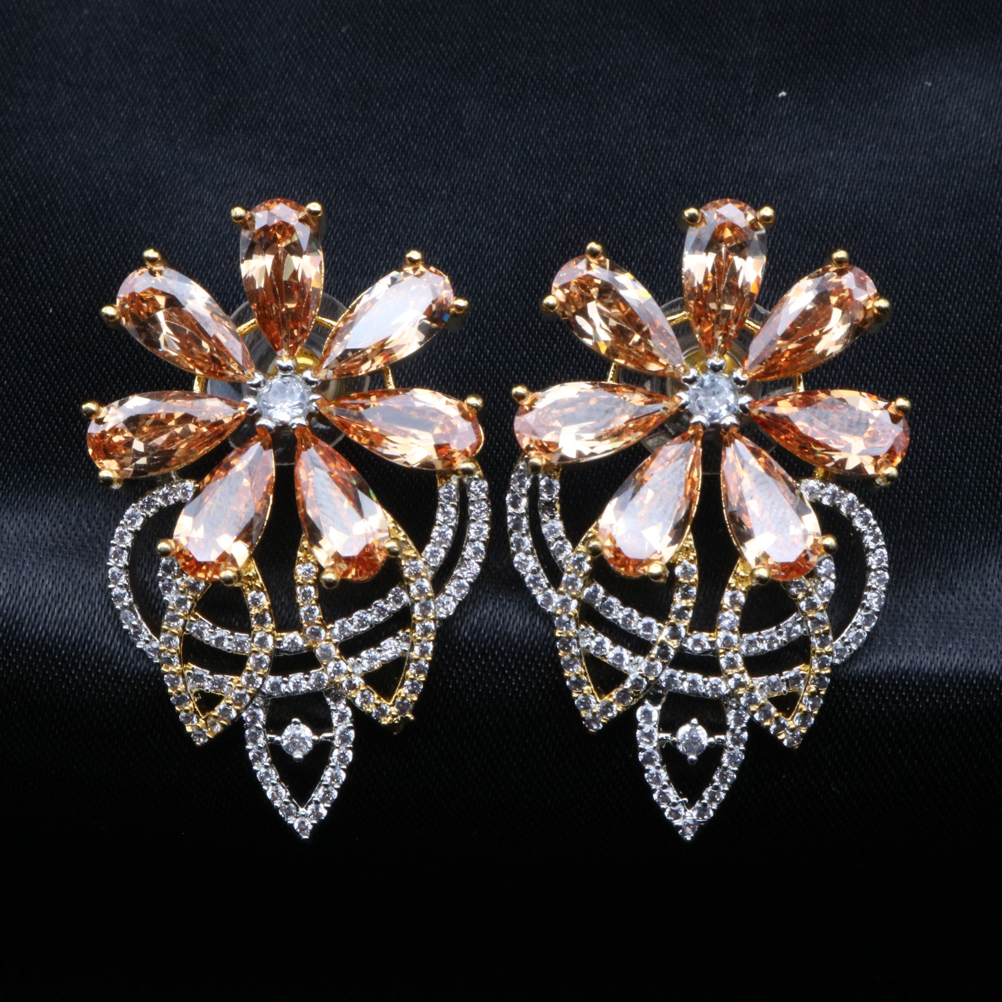 A pair of earrings with a floral pattern, featuring champagne colors, adorned with gold and clear embellishments.