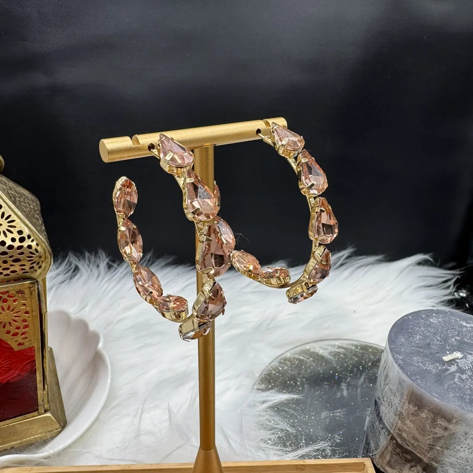 Gold hoop earrings with champagne gemstones on a gold stand against a dark background.