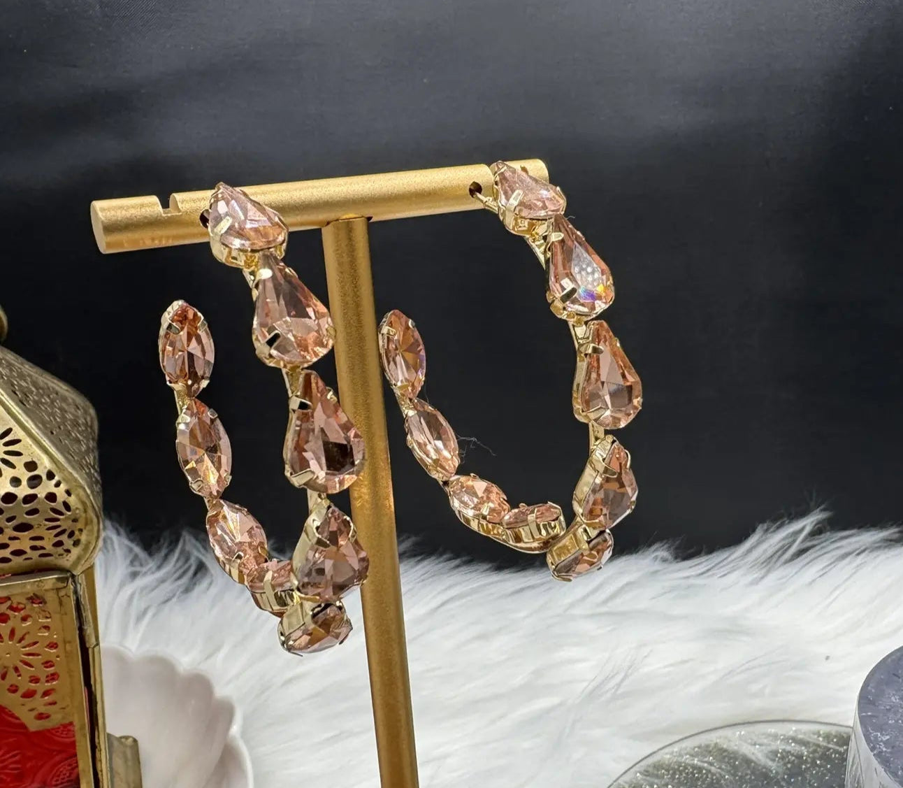 front view of Gold hoop earrings with champagne gemstones on a gold stand against a dark background.