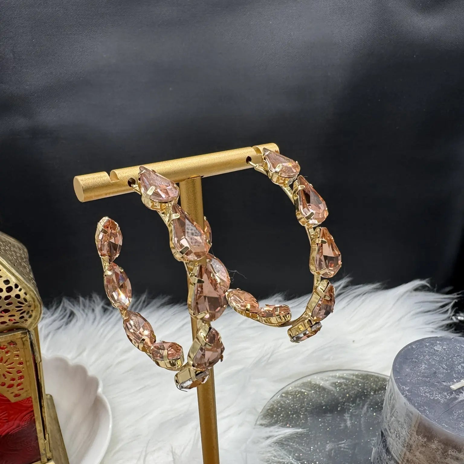 top view of Gold hoop earrings with champagne gemstones on a gold stand against a dark background.