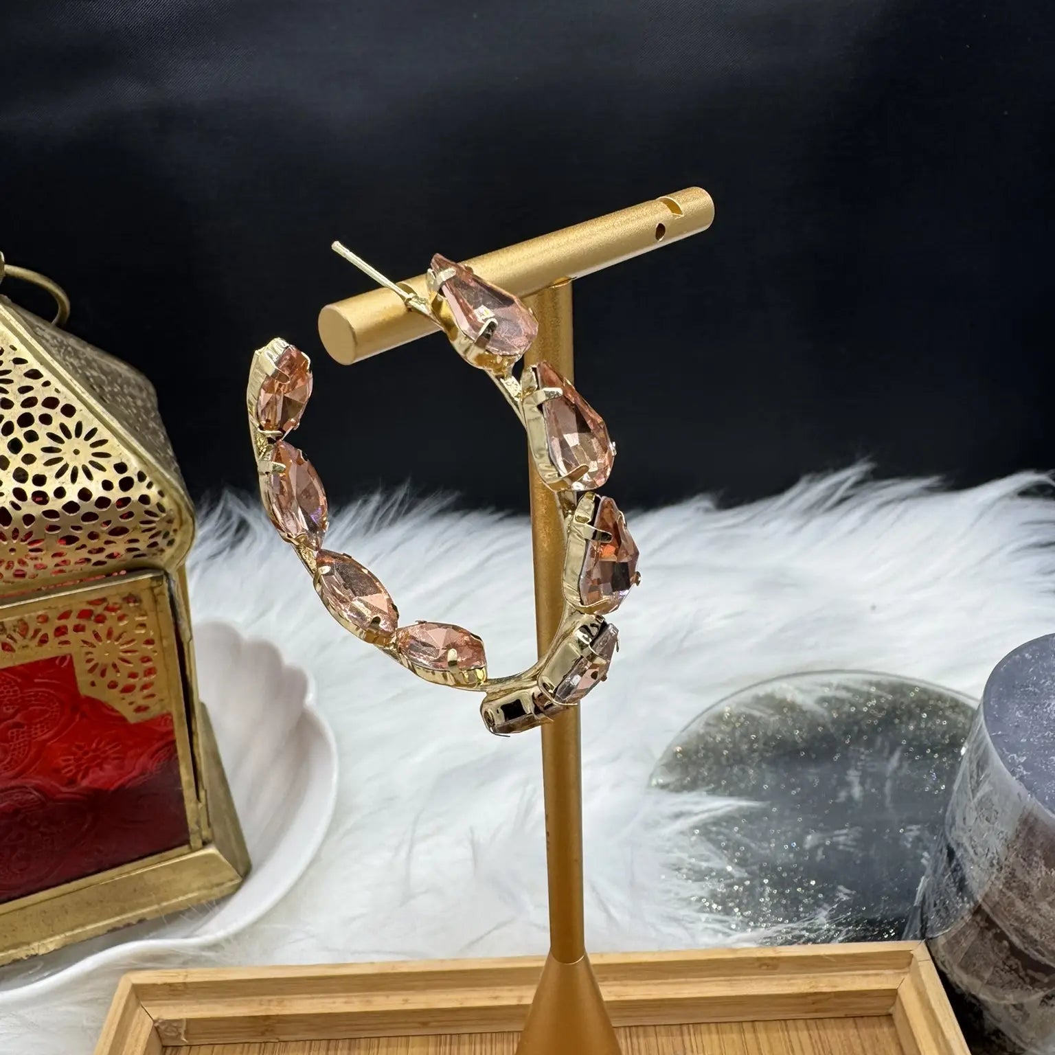 side view of Gold hoop earrings with champagne gemstones on a gold stand against a dark background.