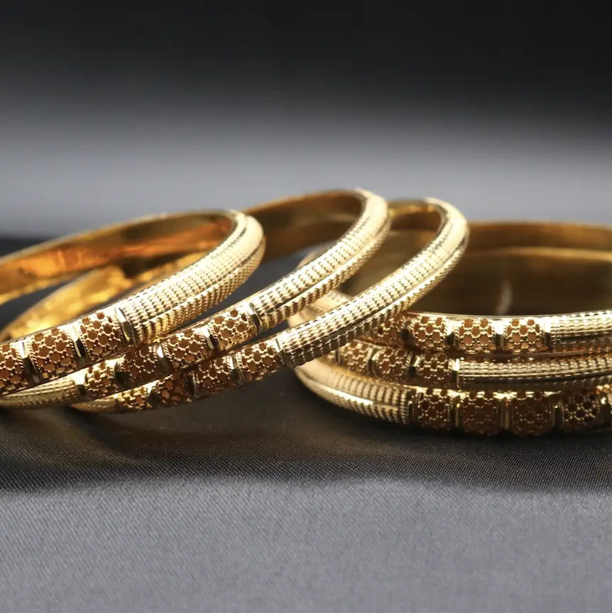 Elegant gold plated bangles set displayed on black satin background