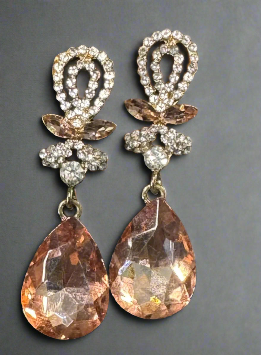 Pair of ornate earrings with teardrop-shaped gemstones on a dark background