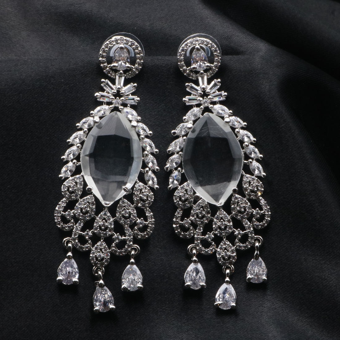 A pair of stainless steel earrings with American diamond accents, featuring a chandelier design with multiple drops.