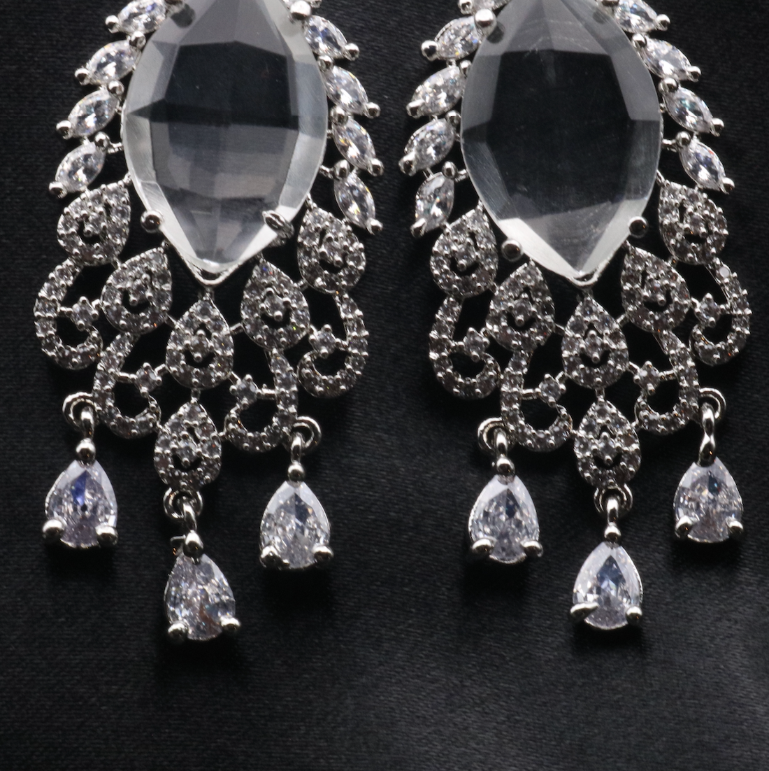 bottom view of pair of stainless steel earrings with American diamond accents, featuring a chandelier design with multiple drops.