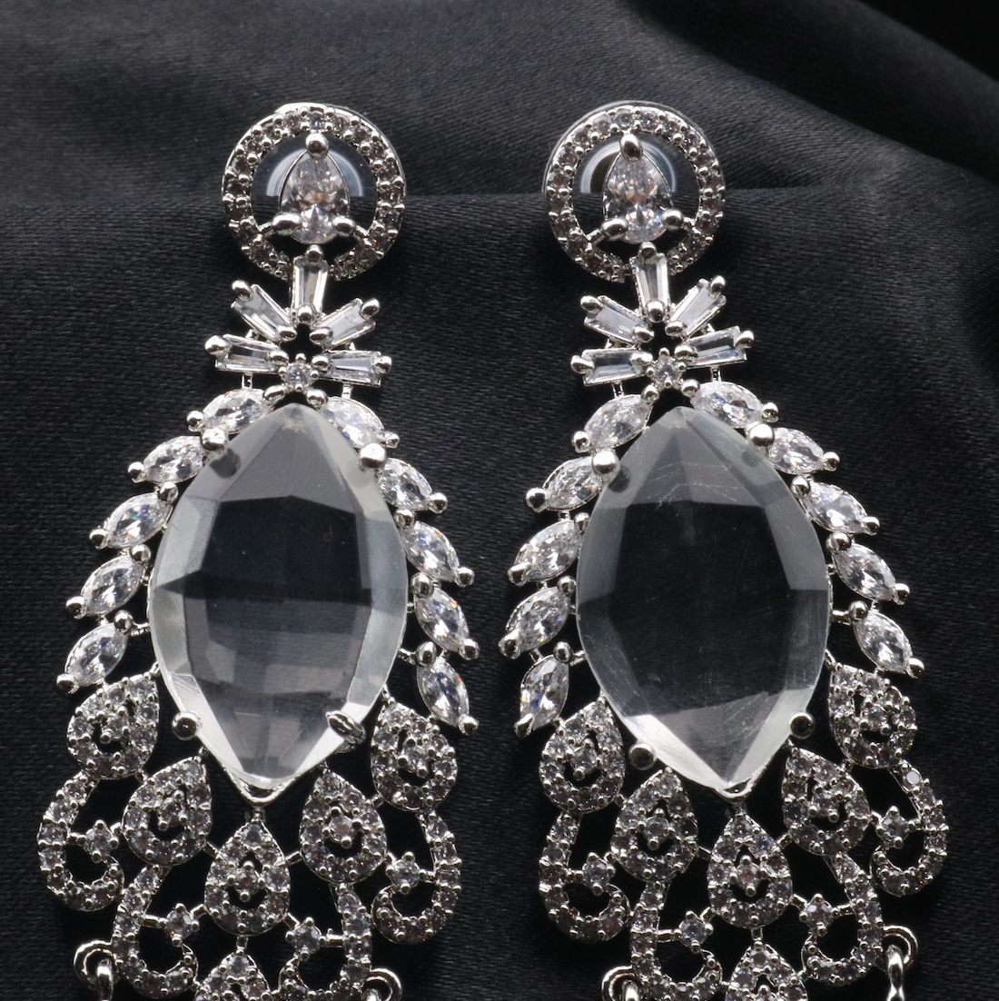 top view of pair of stainless steel earrings with American diamond accents, featuring a chandelier design with multiple drops.