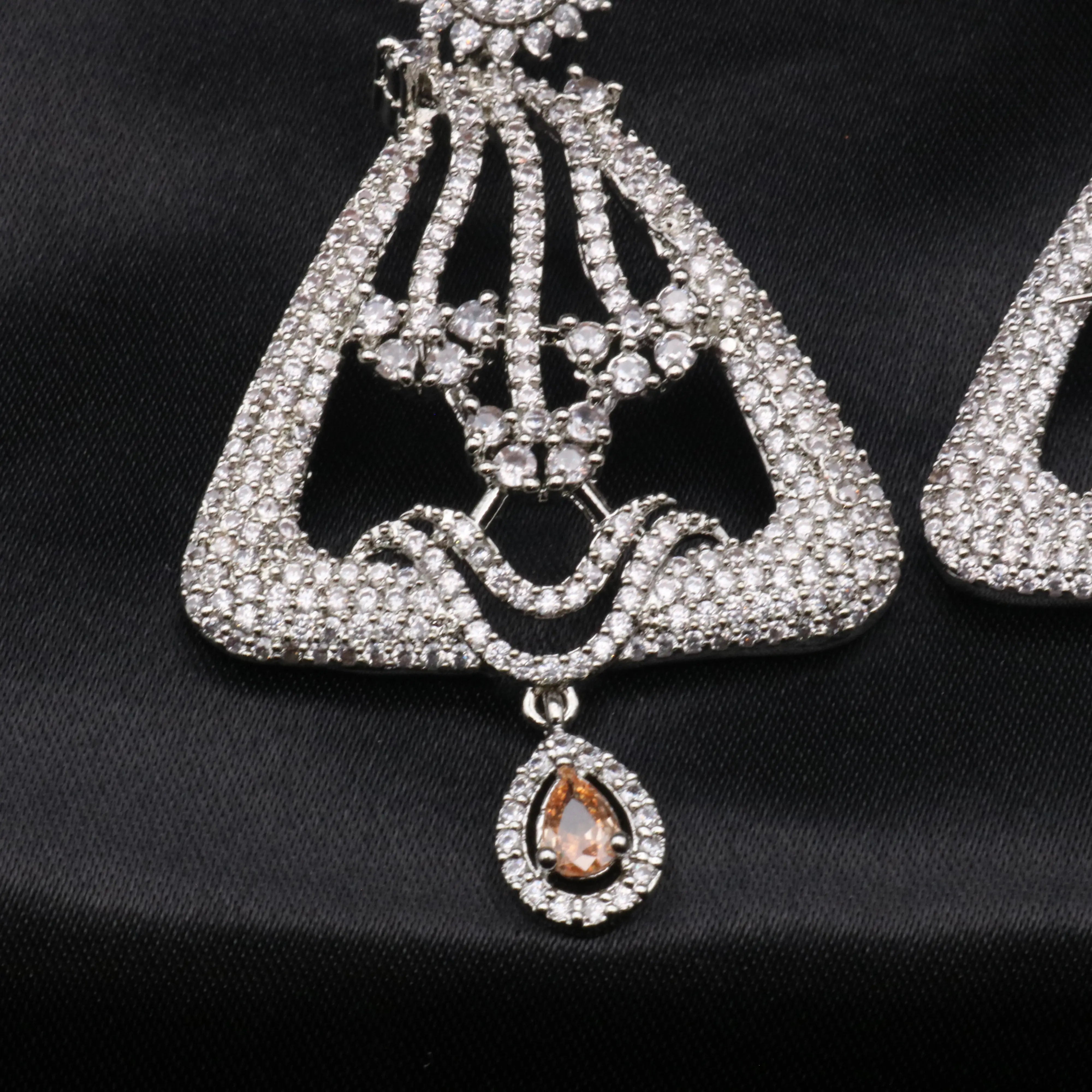 bottom part of silver-colored chandelier earrings with champagne gemstones and intricate detailing, displayed against a black background.