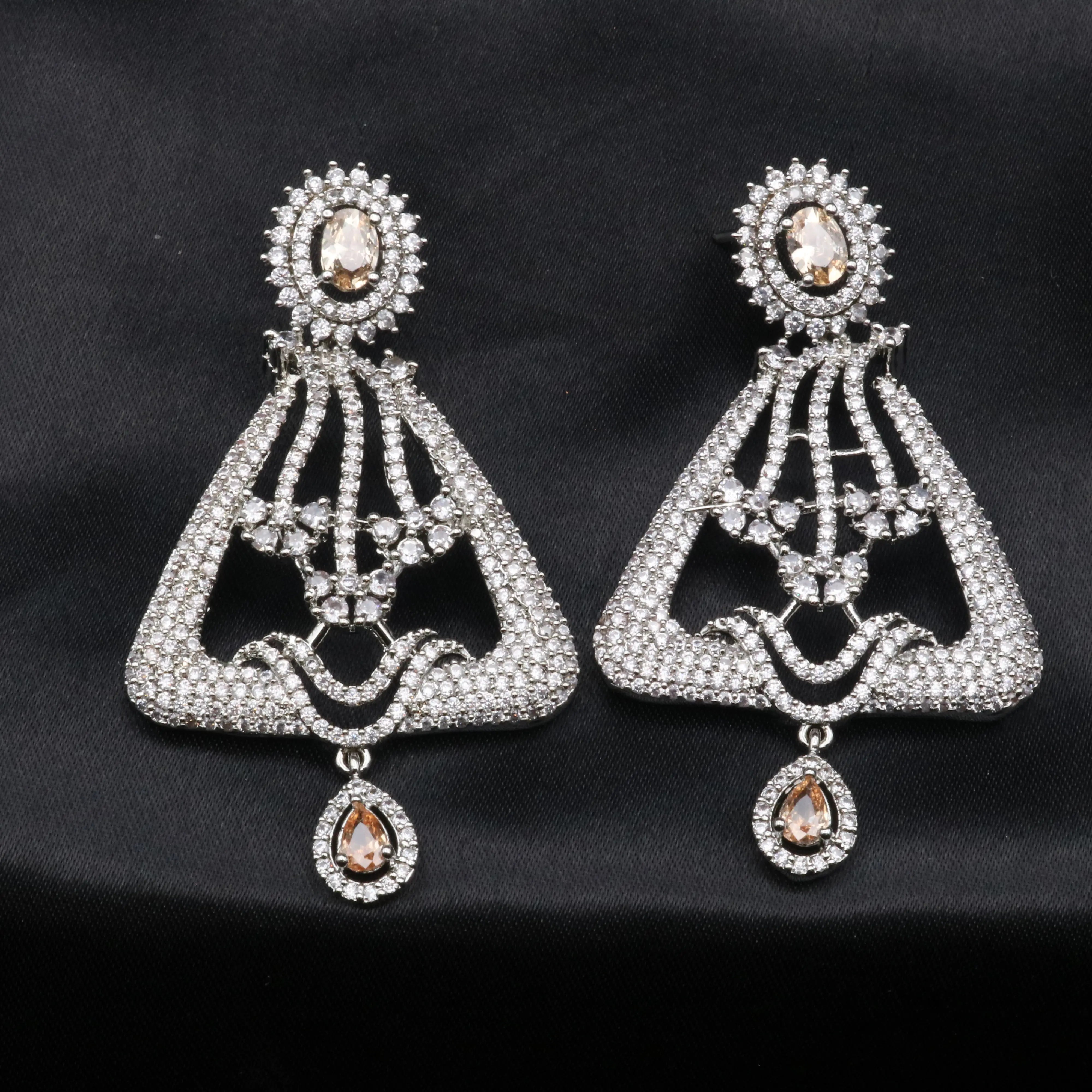A pair of silver-colored chandelier earrings with champagne gemstones and intricate detailing, displayed against a black background.