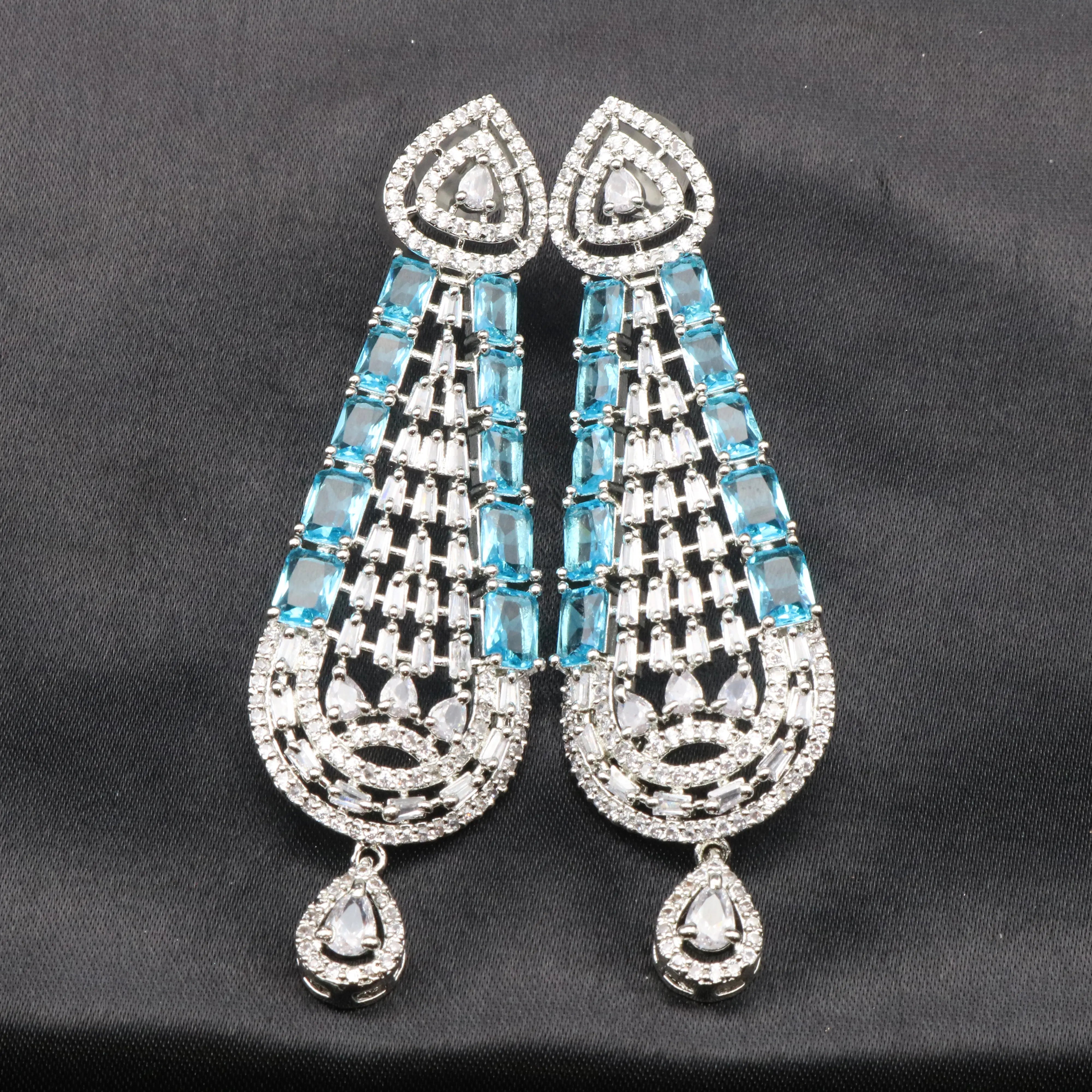 Pair of silver earrings with blue gemstones on a black background