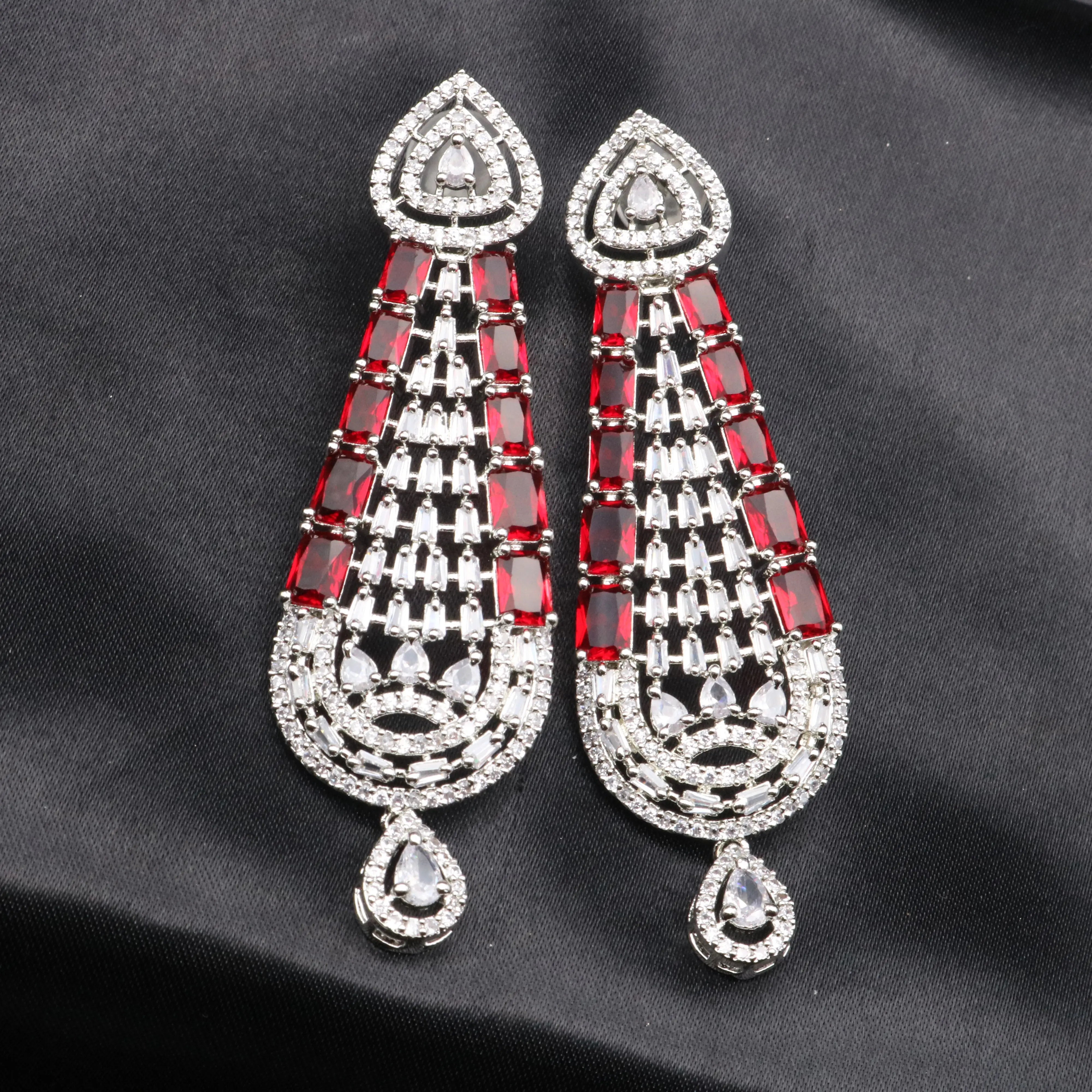 Pair of red and silver American diamonds earrings on a black background